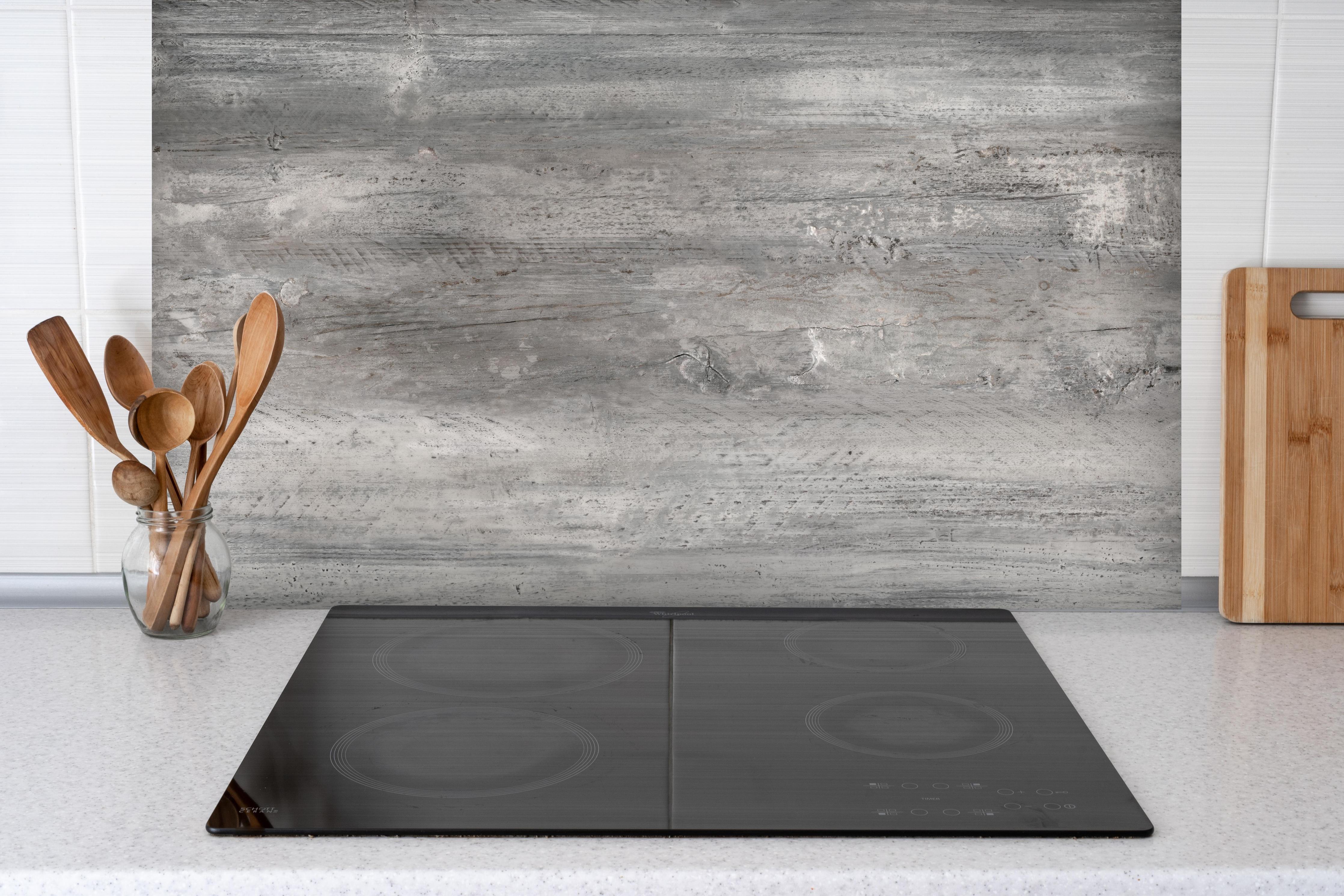 Spritzschutz - Gräuliche alte Holztextur hinter einem Cerankochfeld zwischen Holz-Kochutensilien