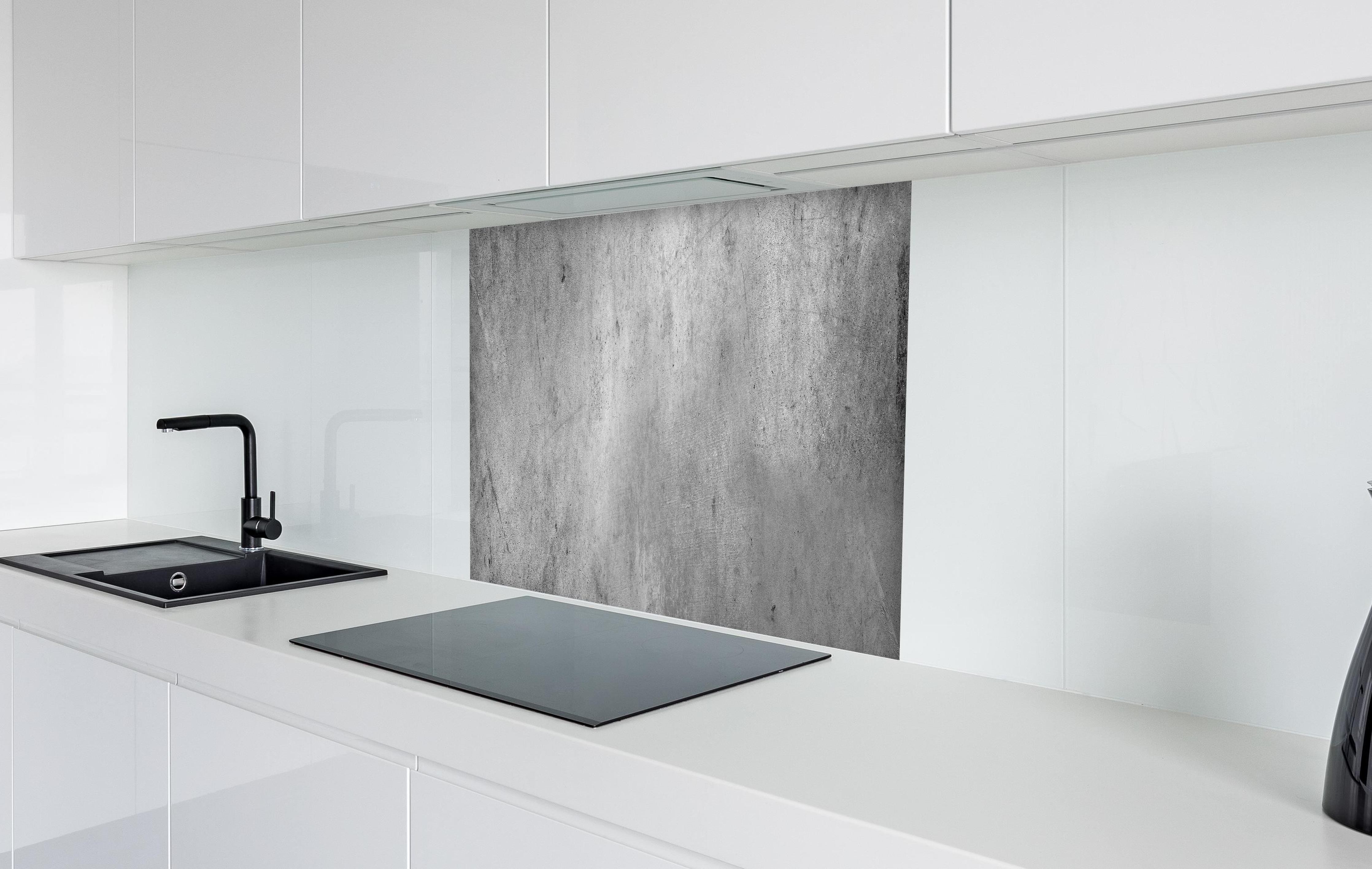 Spritzschutz - Gräulicher rauer Beton in weißer Hochglanz-Küche hinter einem Cerankochfeld