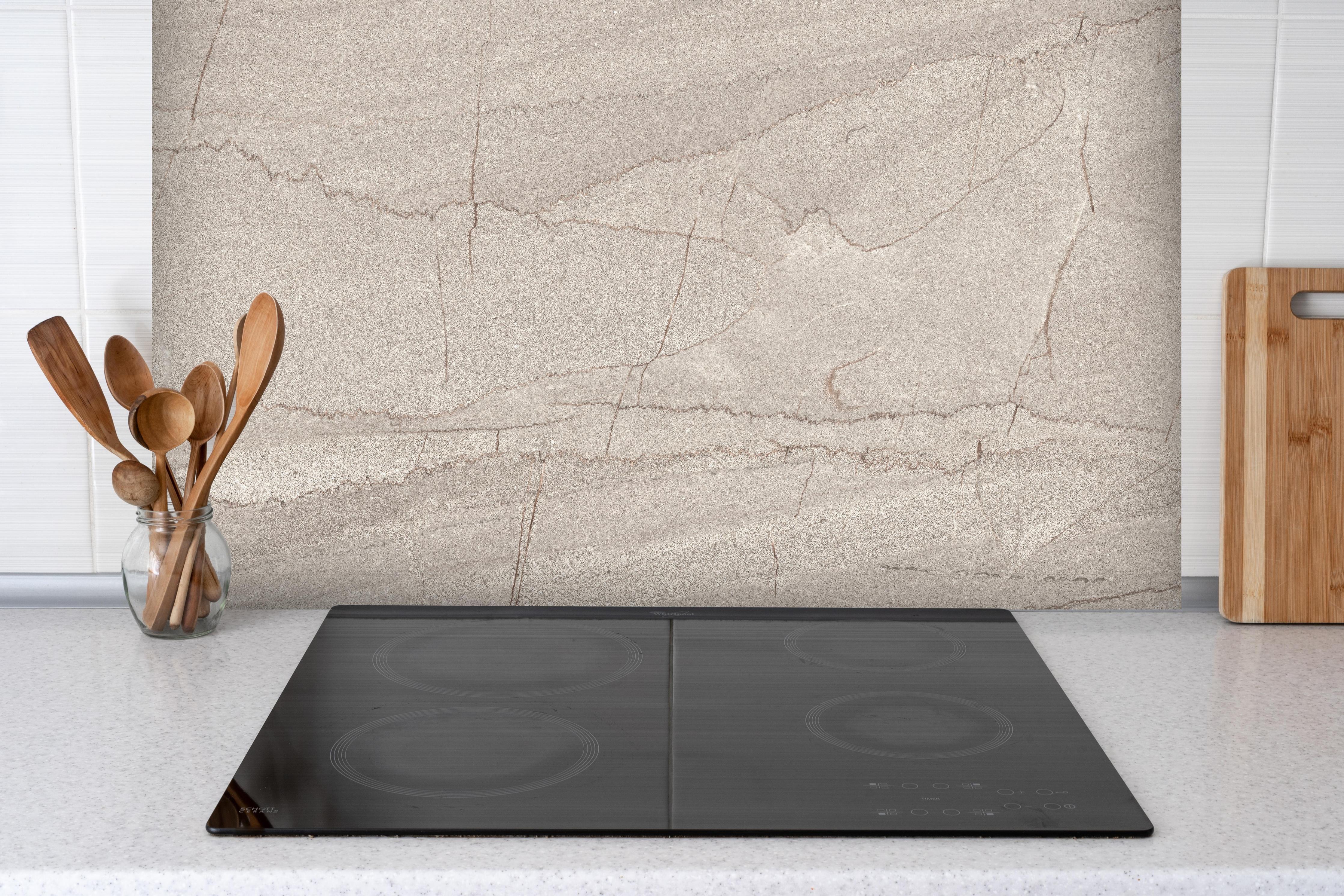 Spritzschutz - Gräulicher rissiger Marmor hinter einem Cerankochfeld zwischen Holz-Kochutensilien