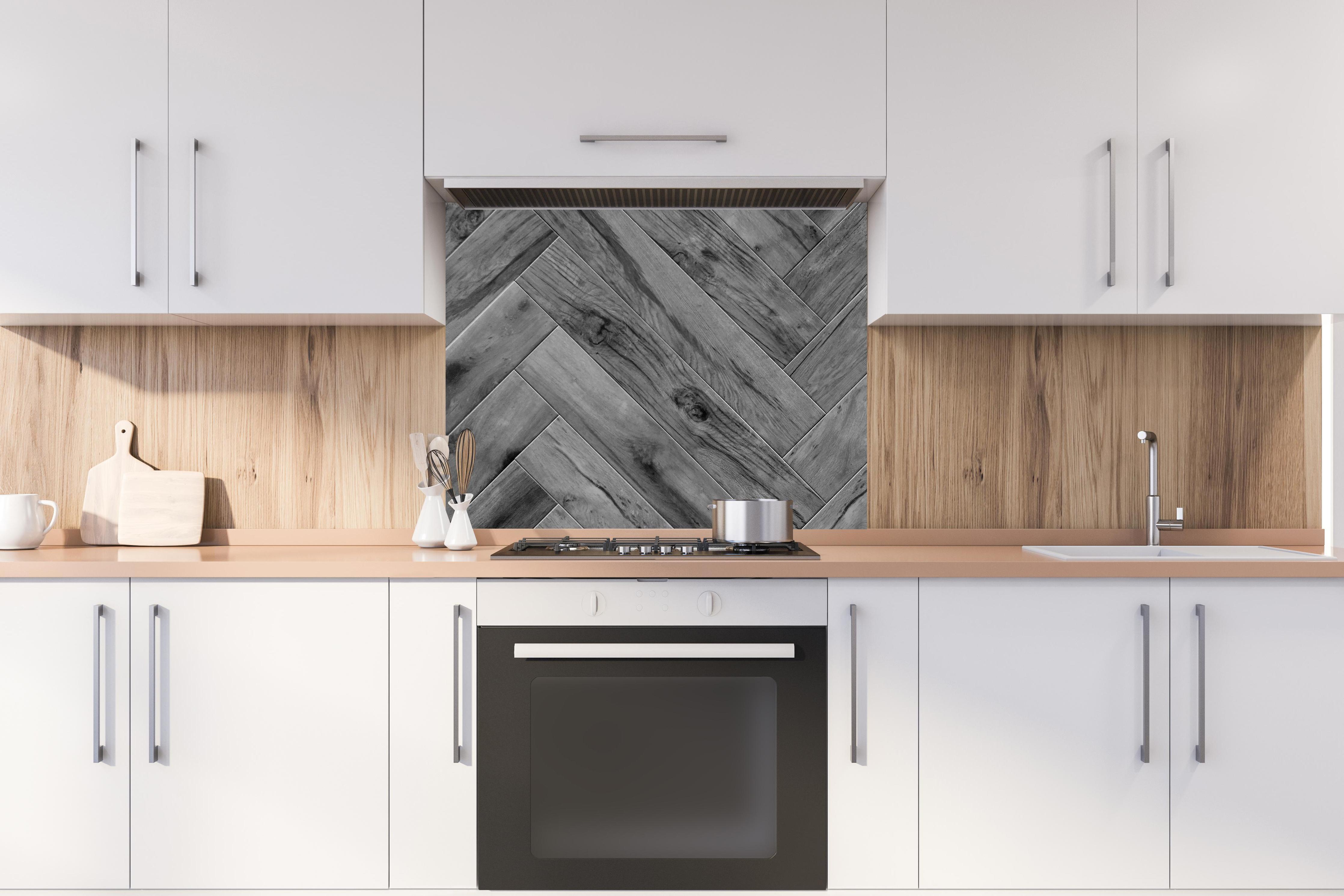 Spritzschutz - Gräuliches Holzparkett mit Fischgrätenmuster hinter stilvollem Gasherd unter Dunstabzugshaube
