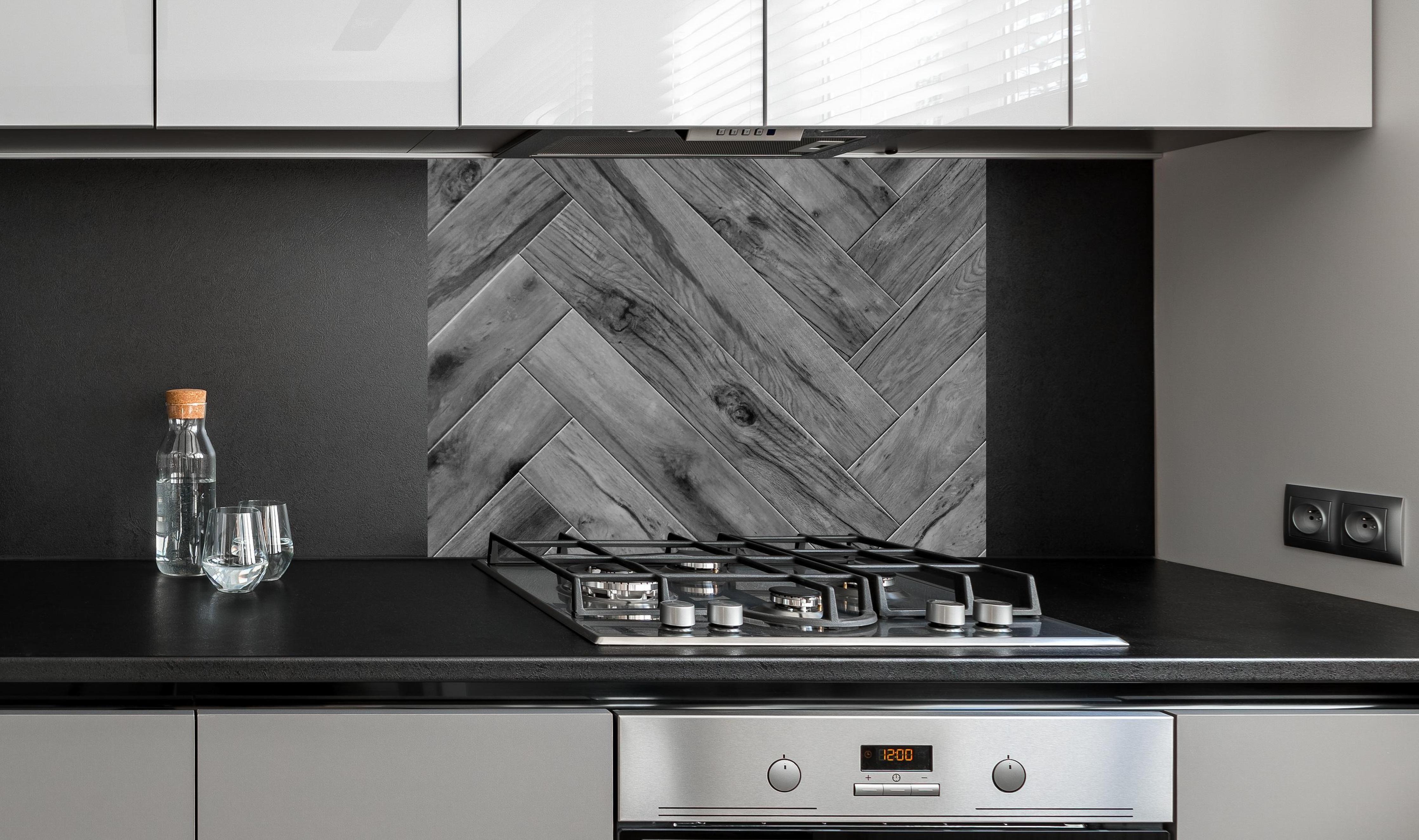 Spritzschutz - Gräuliches Holzparkett mit Fischgrätenmuster an edler Anthrazit-Wand hinter silbernem Gasherd