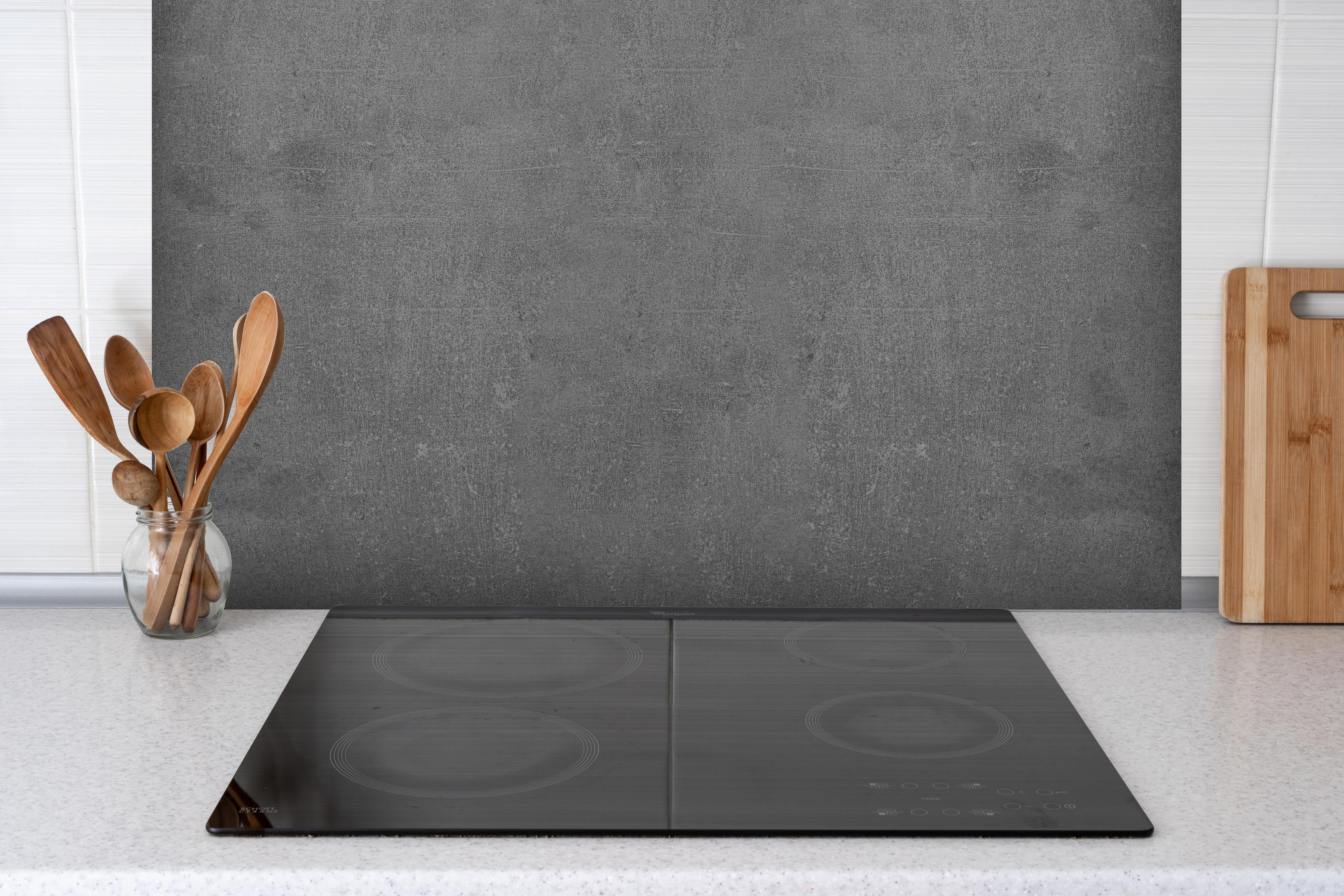 Spritzschutz - Graue Anthrazite Beton Textur hinter einem Cerankochfeld zwischen Holz-Kochutensilien