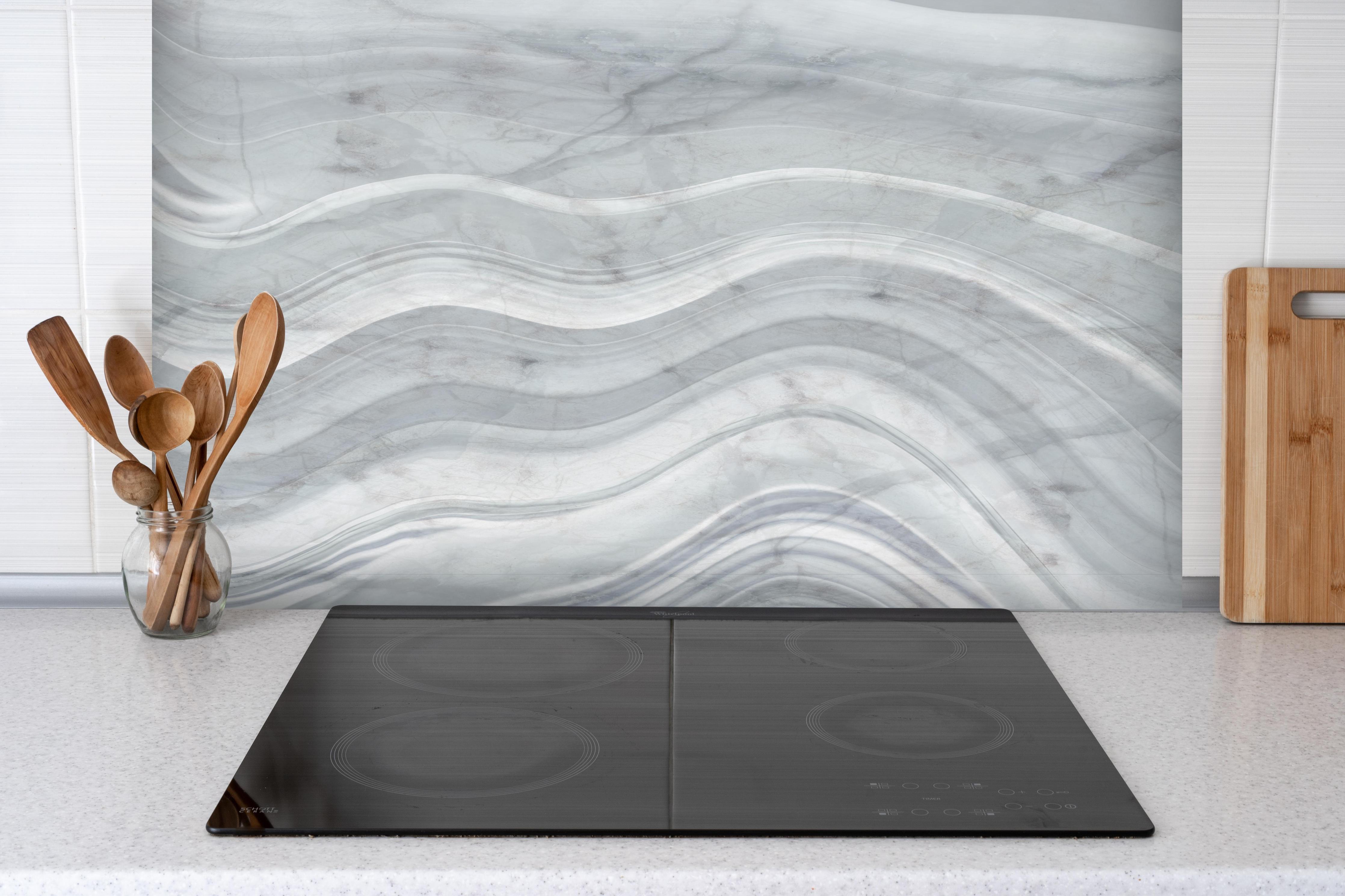Spritzschutz - Graue wellenförmige Marmor Textur hinter einem Cerankochfeld zwischen Holz-Kochutensilien