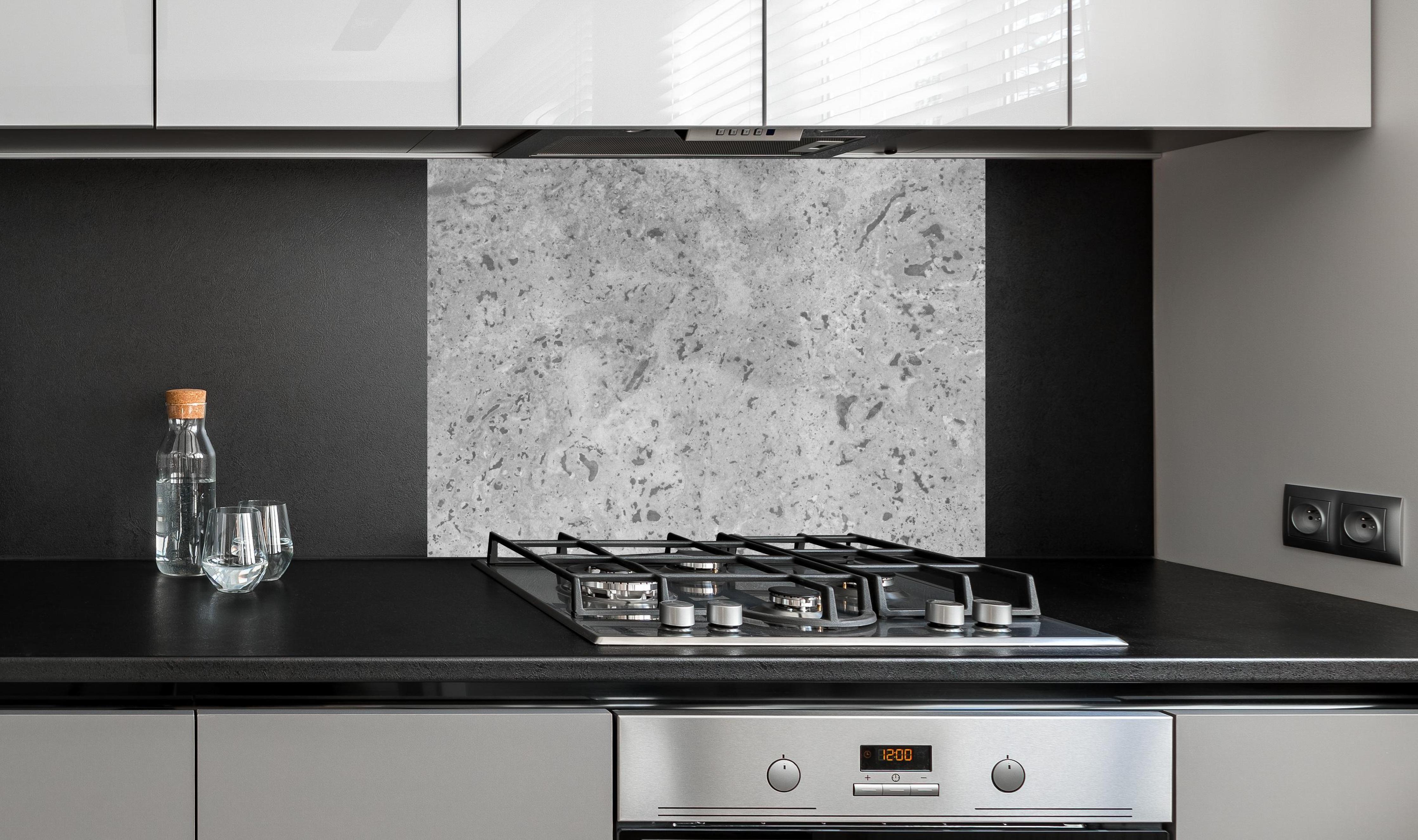 Spritzschutz - Grauer Beton an edler Anthrazit-Wand hinter silbernem Gasherd