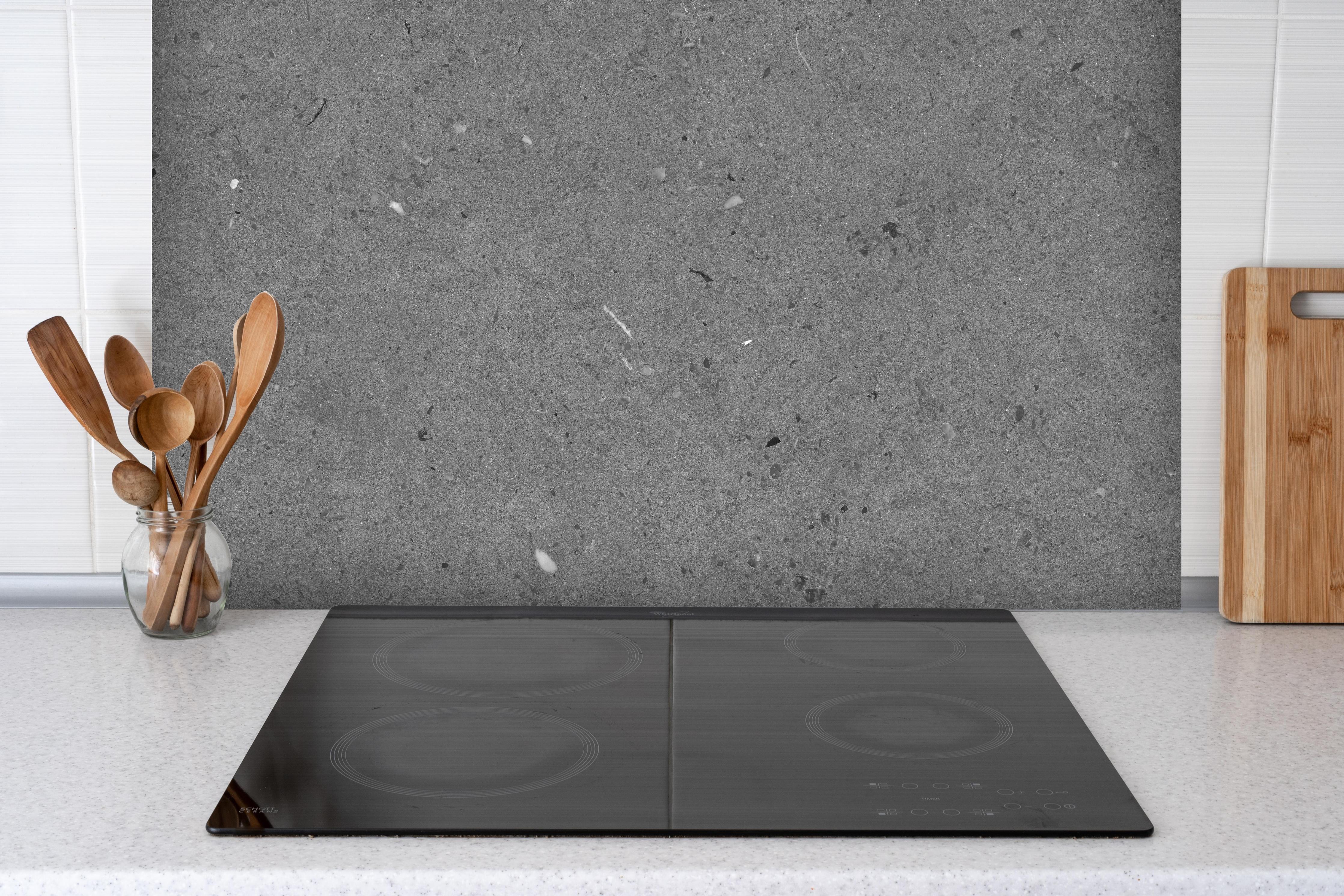 Spritzschutz - Grauer Marmor im Asphaltdesign hinter einem Cerankochfeld zwischen Holz-Kochutensilien