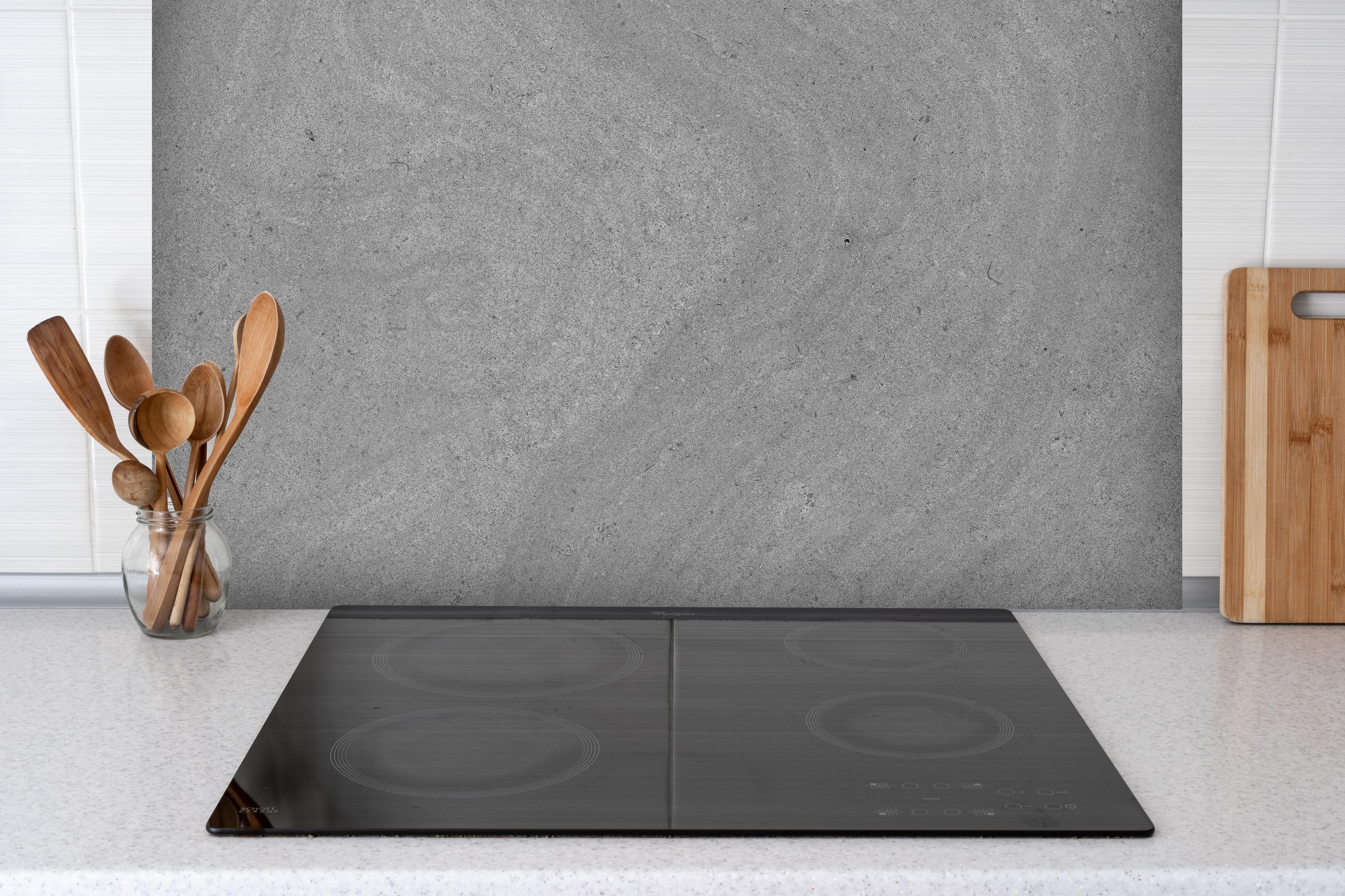 Spritzschutz - Grauer krauser Marmor hinter einem Cerankochfeld zwischen Holz-Kochutensilien