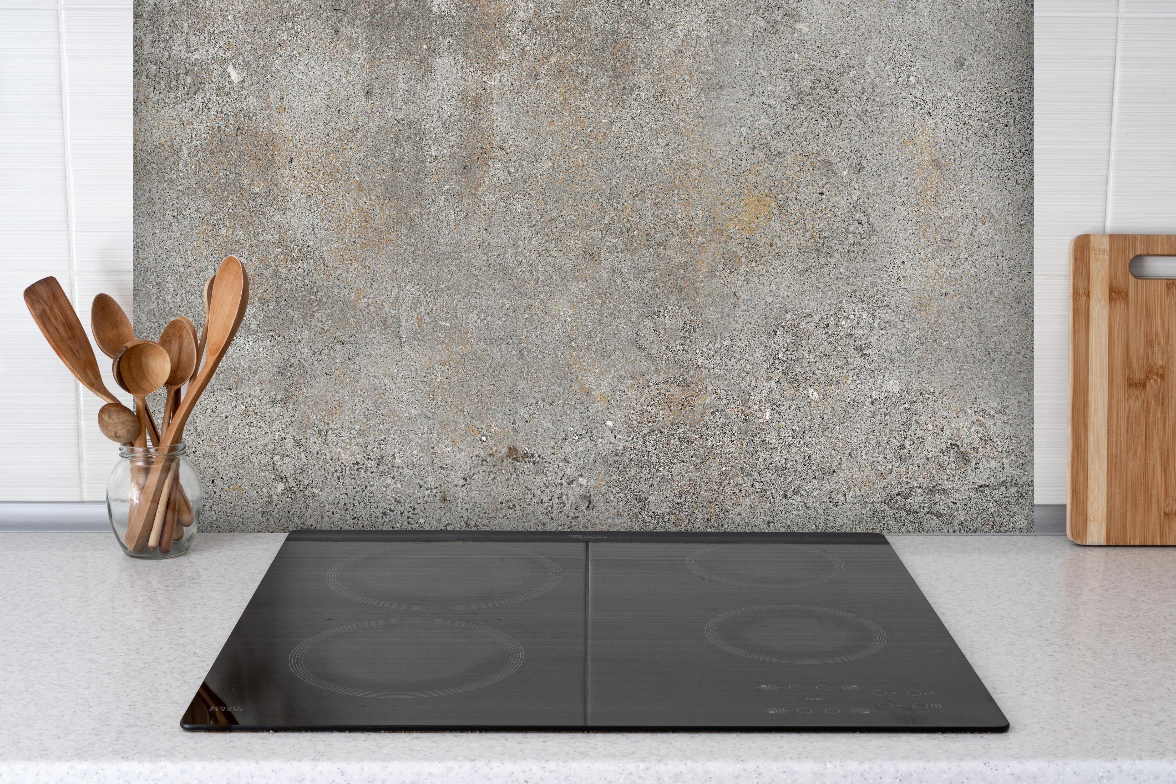 Spritzschutz - Grauer rustikaler Beton hinter einem Cerankochfeld zwischen Holz-Kochutensilien