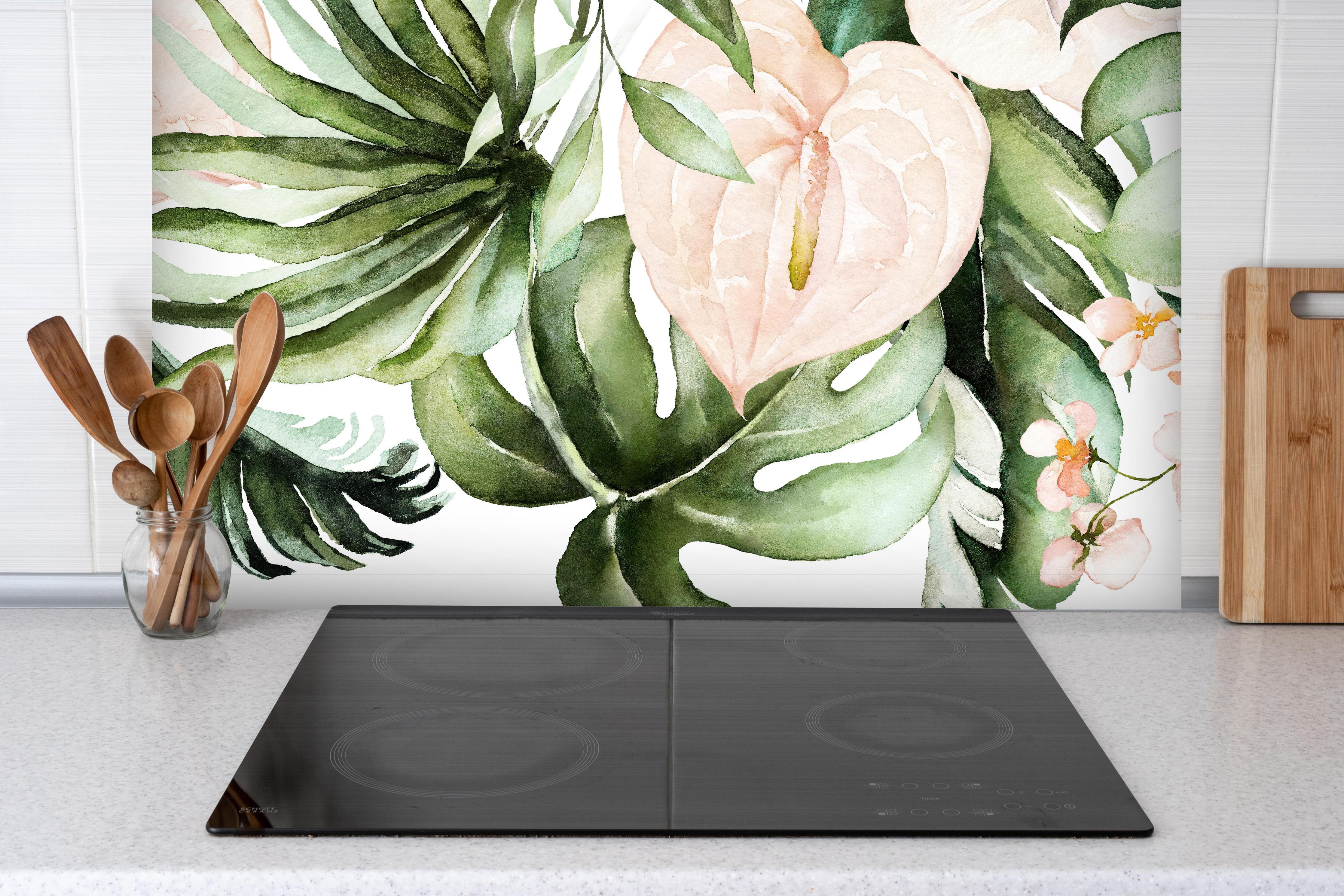 Spritzschutz - Grüne tropische Blätter mit Blüten hinter einem Cerankochfeld zwischen Holz-Kochutensilien