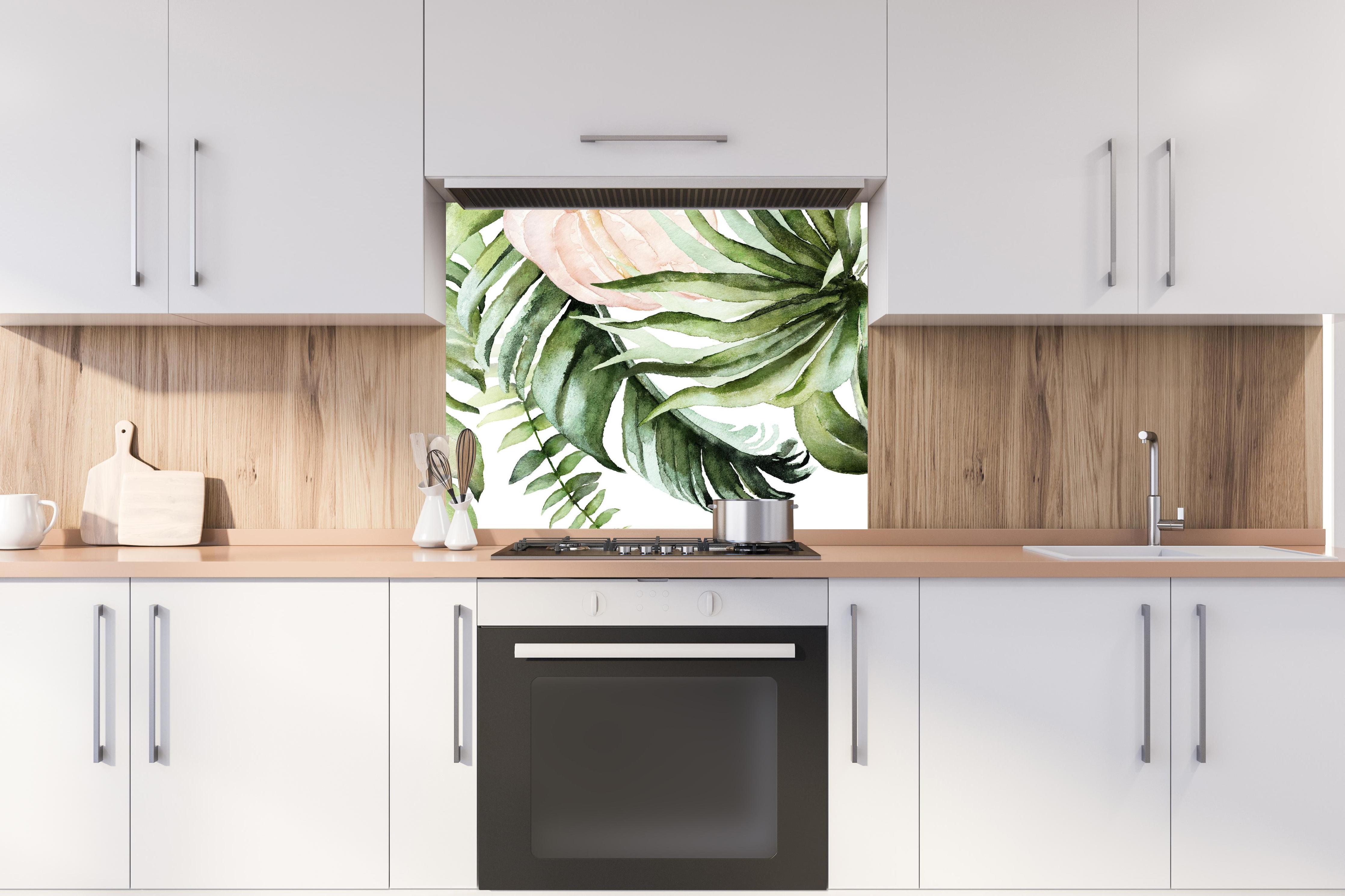 Spritzschutz - Grüne tropische Blätter mit Blüten hinter stilvollem Gasherd unter Dunstabzugshaube