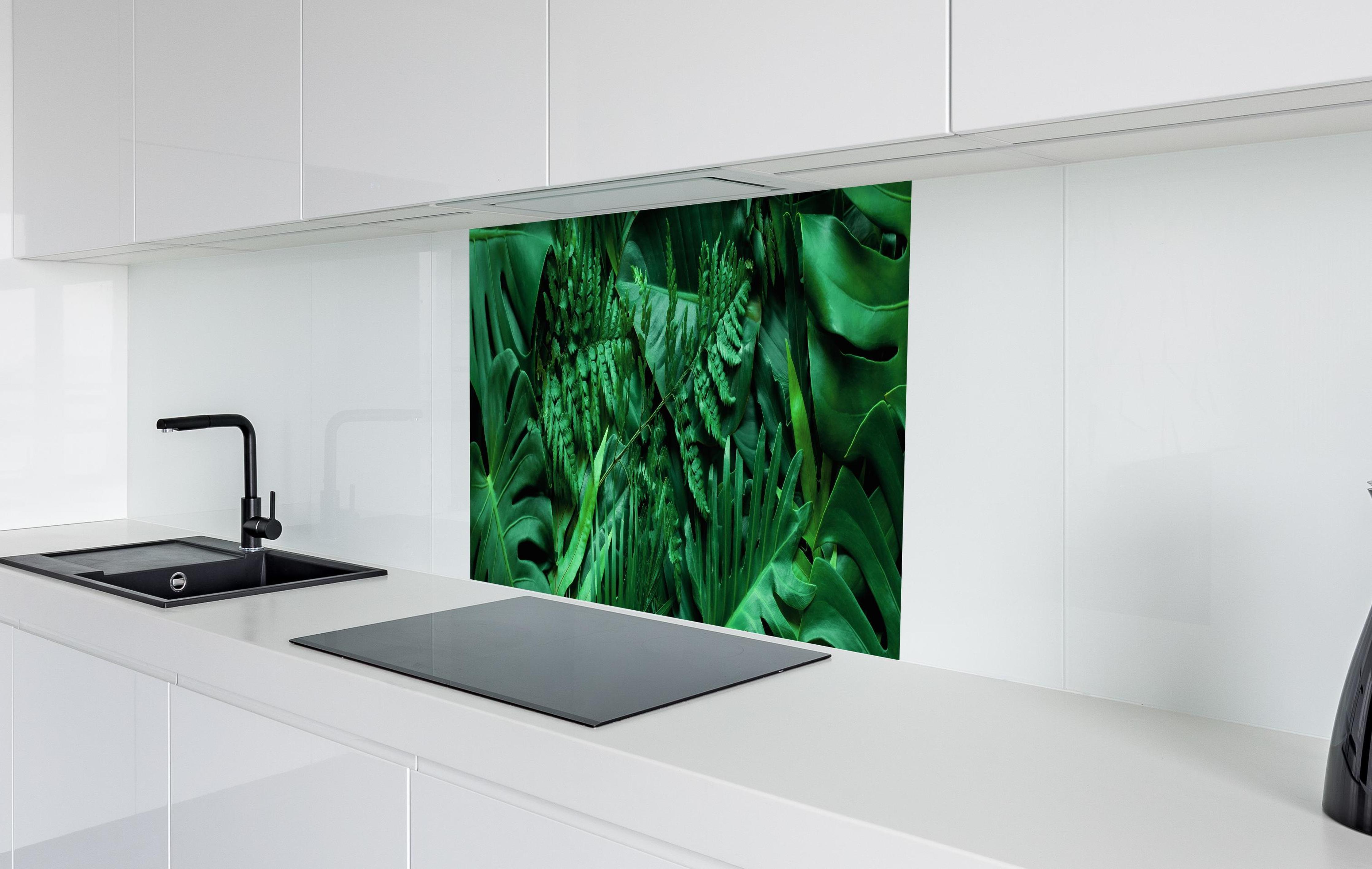 Spritzschutz - Grüne tropische Natur in weißer Hochglanz-Küche hinter einem Cerankochfeld