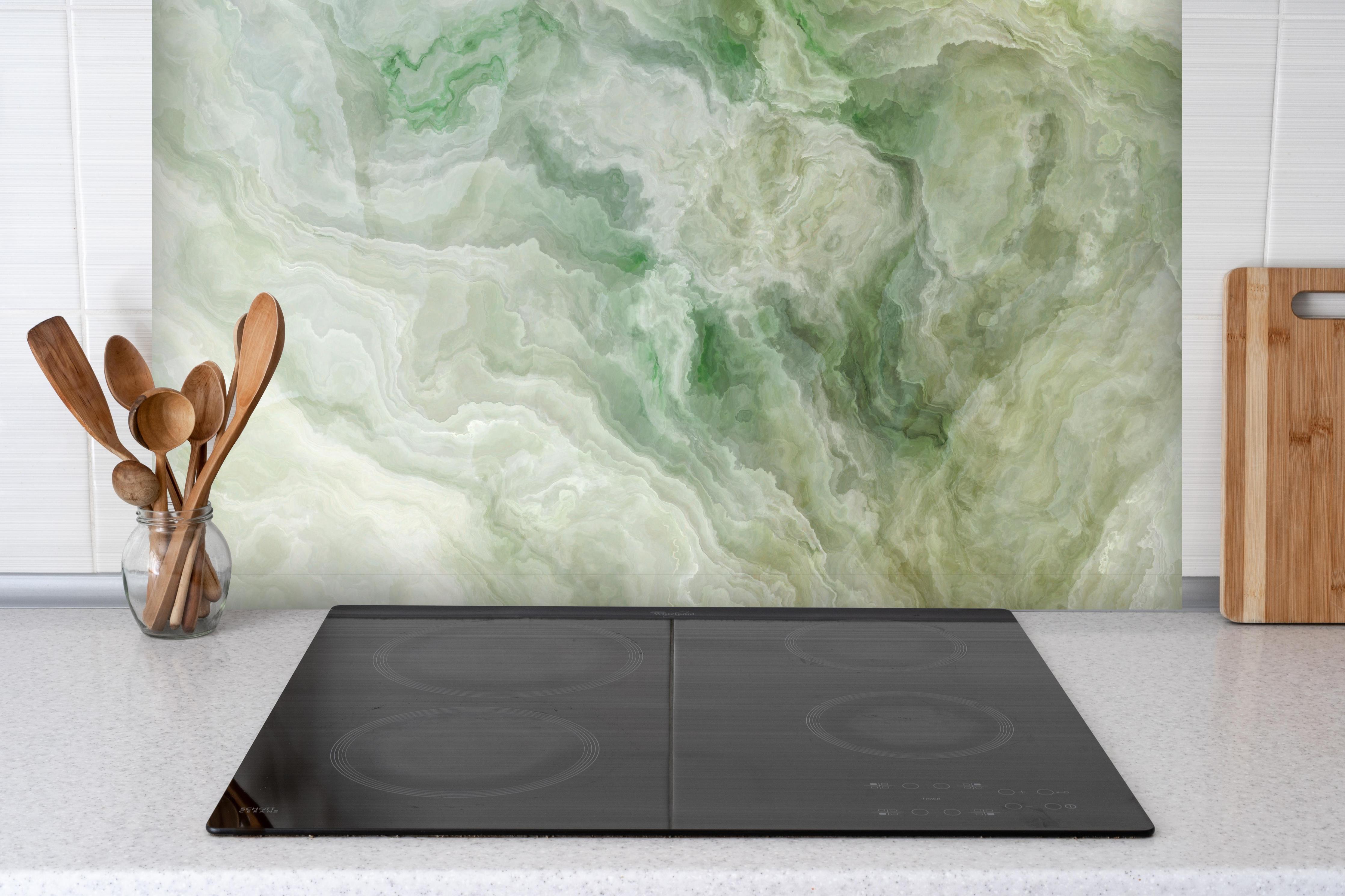 Spritzschutz - Grünlicher Onyx hinter einem Cerankochfeld zwischen Holz-Kochutensilien