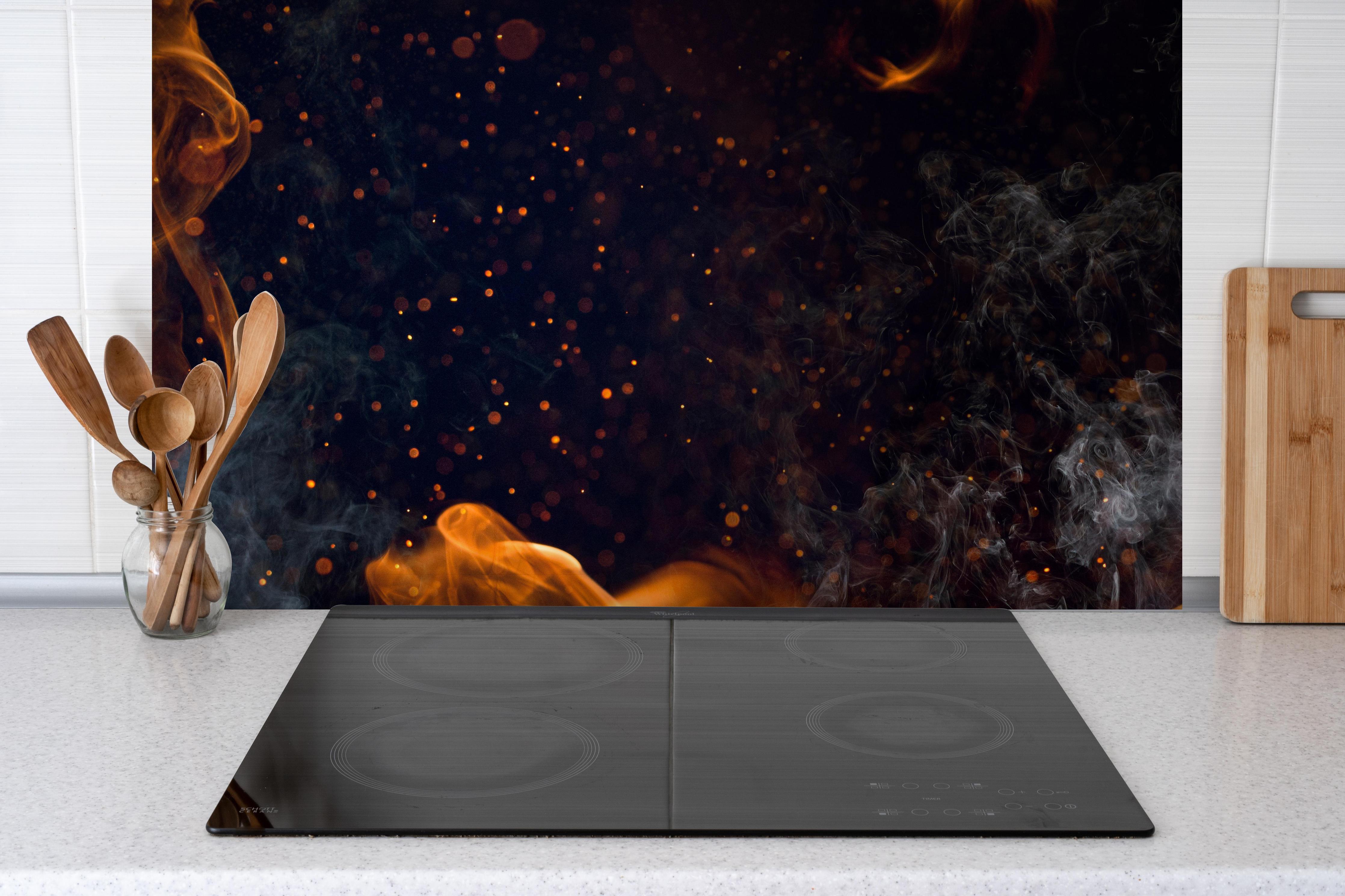 Spritzschutz - Heißes Lagerfeuer mit Rauch hinter einem Cerankochfeld zwischen Holz-Kochutensilien