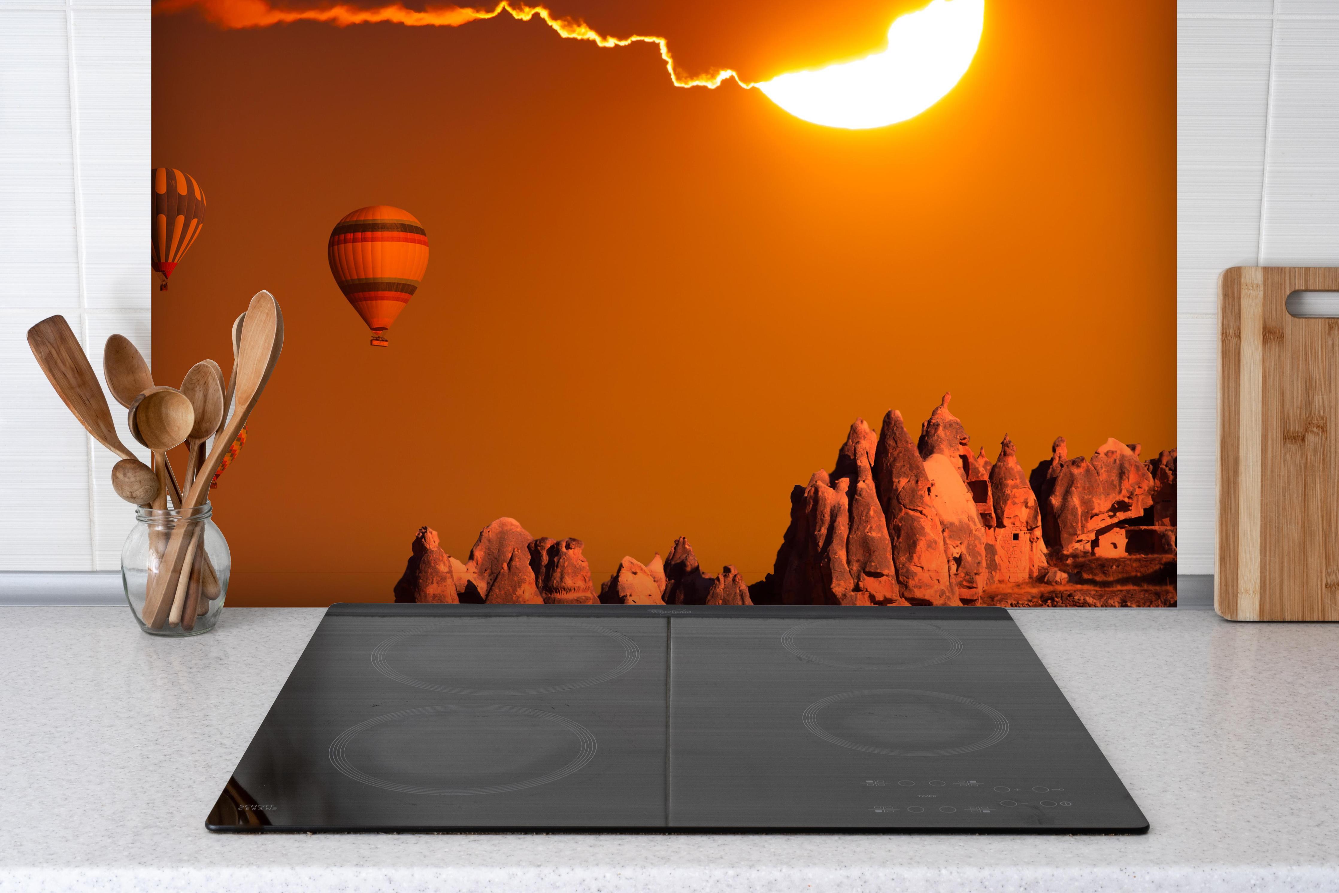 Spritzschutz - Heißluftballons bei rötlichem Himmel hinter einem Cerankochfeld zwischen Holz-Kochutensilien