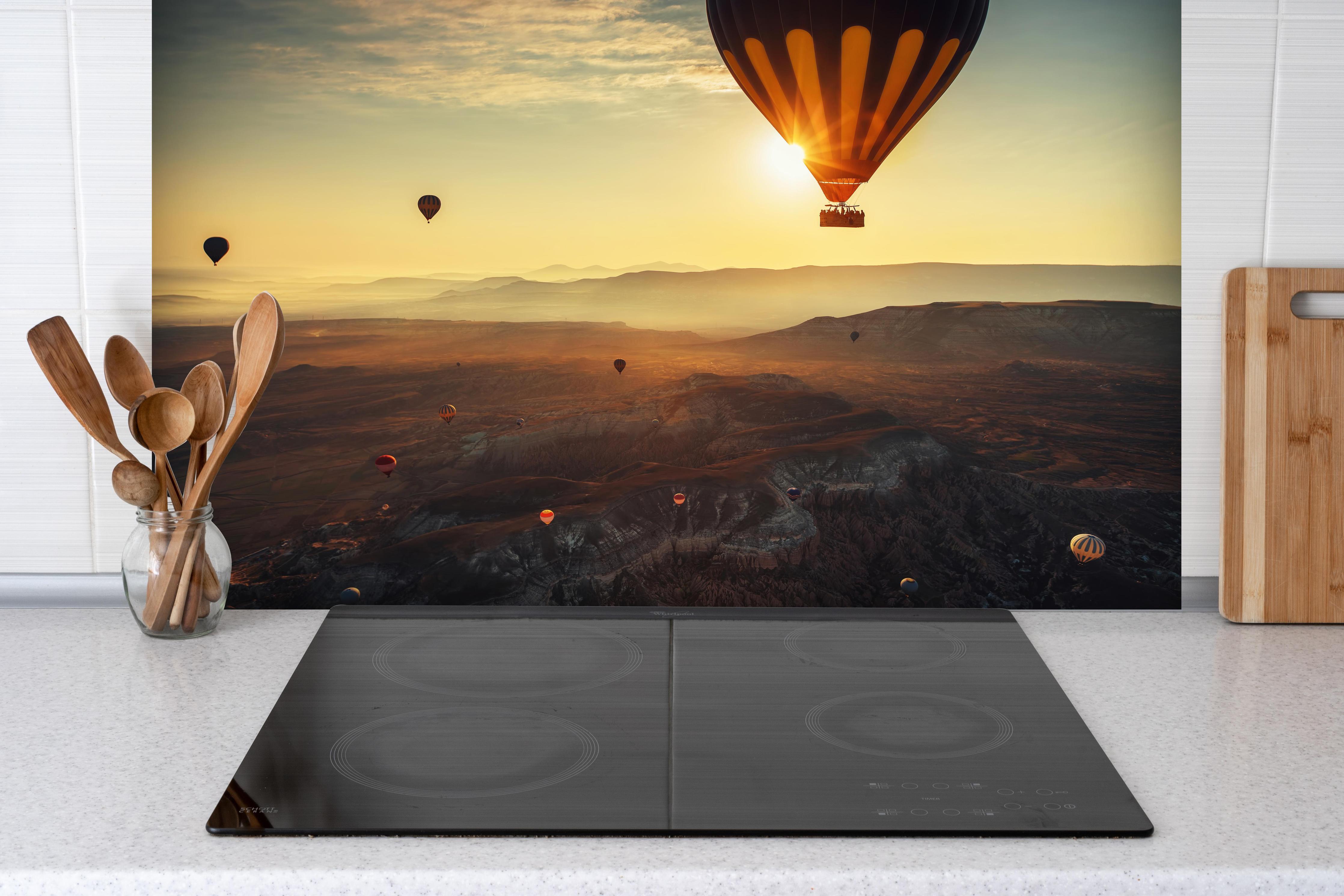 Spritzschutz - Heißluftballons fliegen über das Tal von Kappadokien hinter einem Cerankochfeld zwischen Holz-Kochutensilien