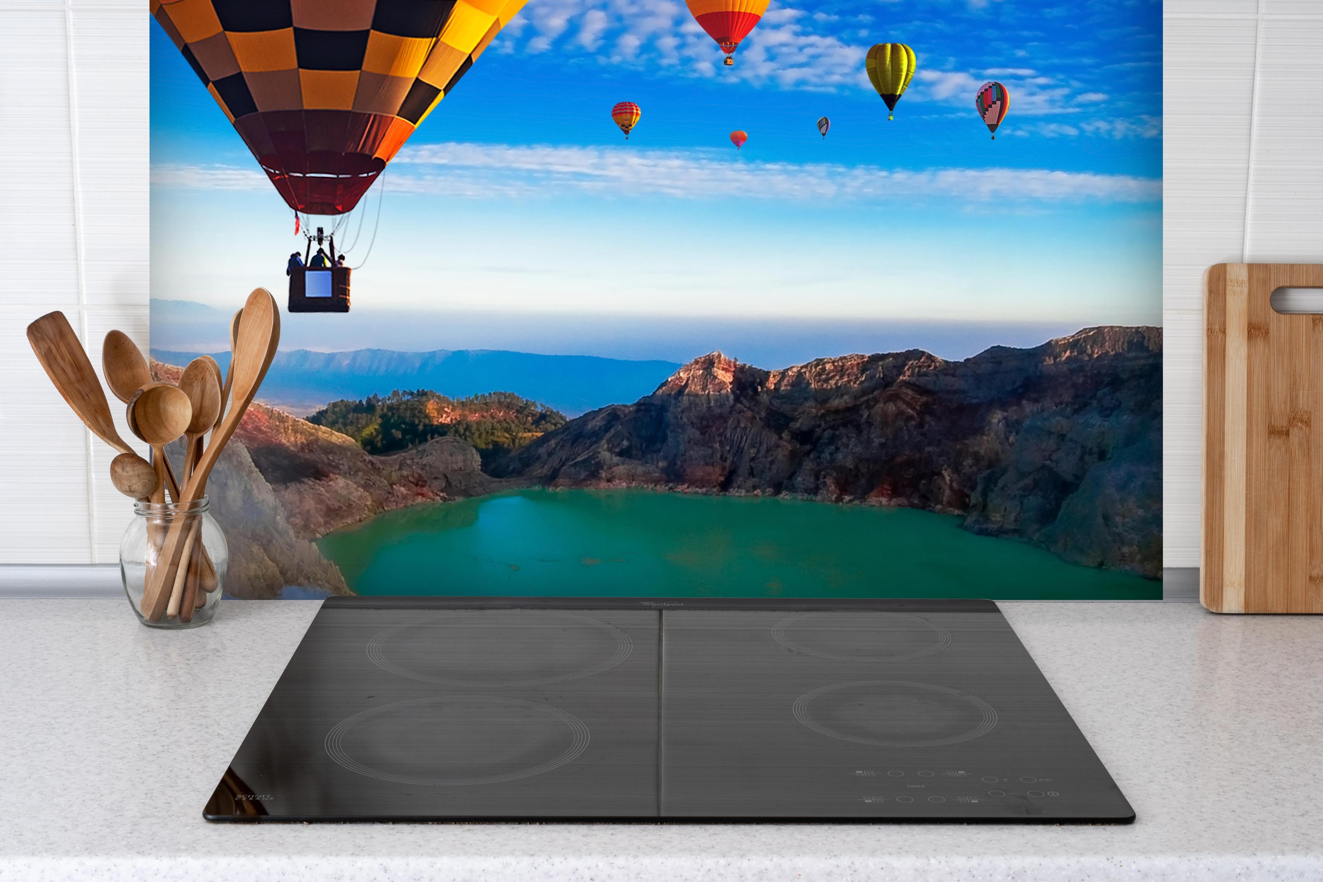 Spritzschutz - Heißluftballons über dem Krater Kawah Ijen hinter einem Cerankochfeld zwischen Holz-Kochutensilien