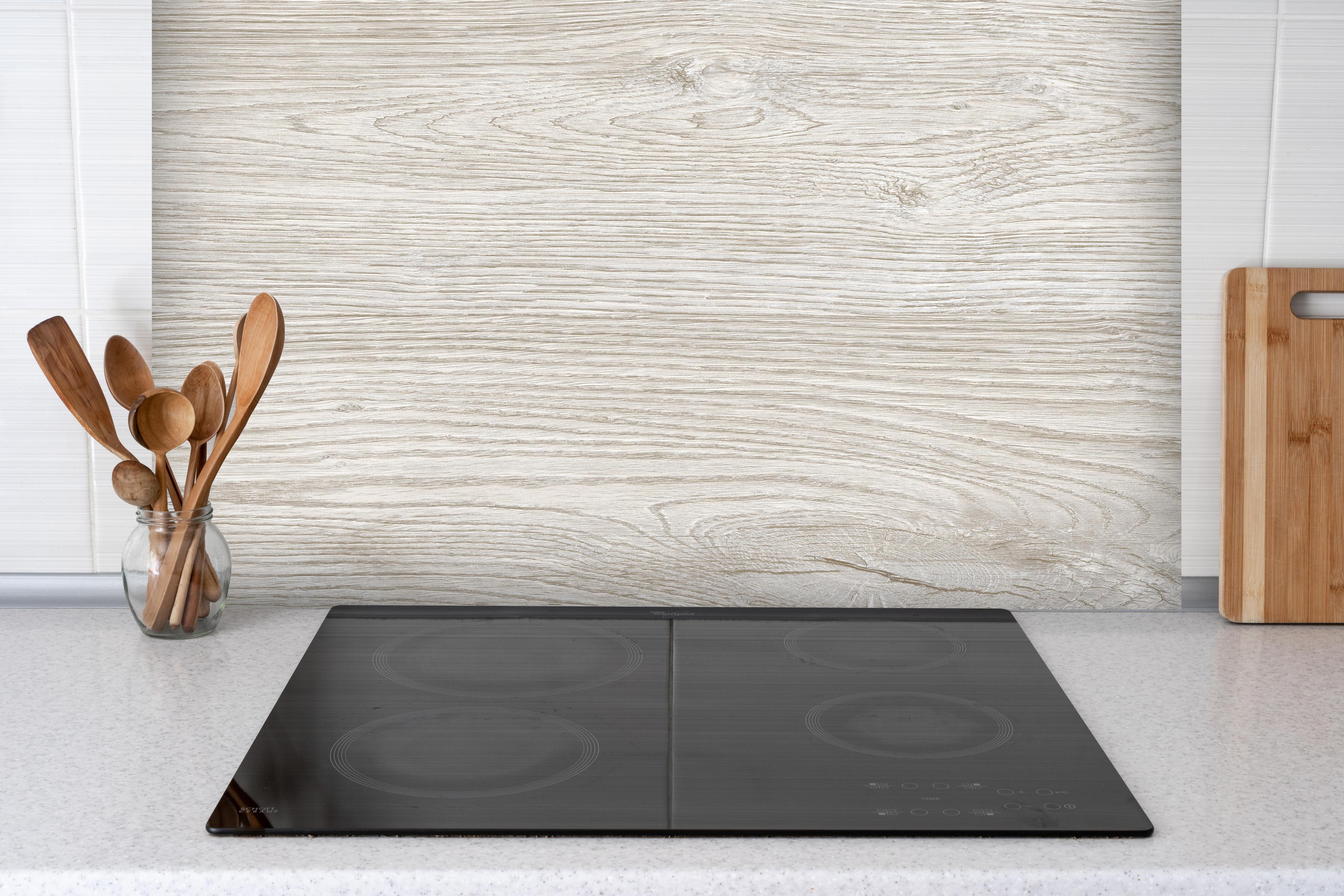 Spritzschutz - Helles Eichenholz hinter einem Cerankochfeld zwischen Holz-Kochutensilien