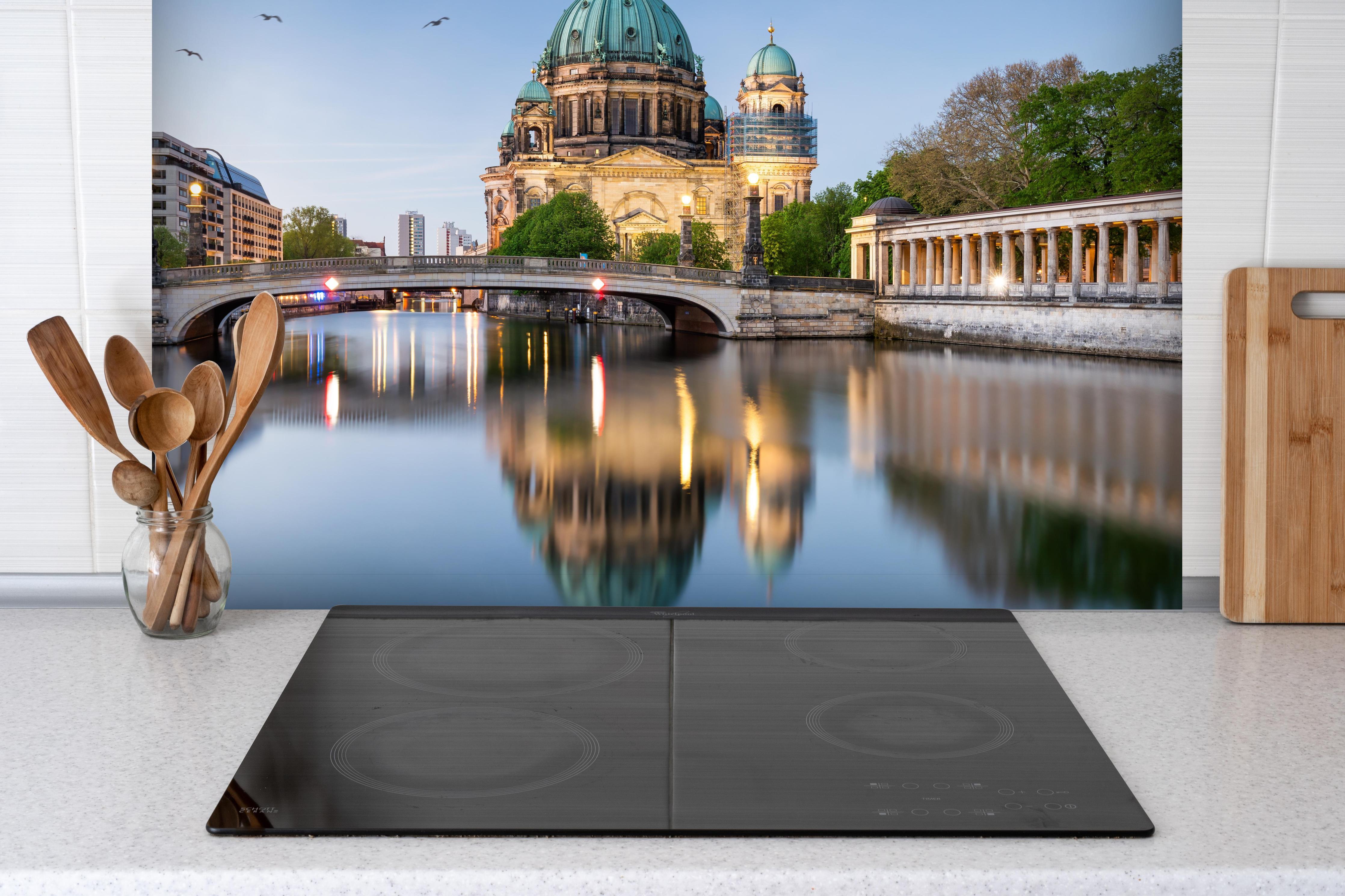 Spritzschutz - Historischer Anblick Berliner Dom hinter einem Cerankochfeld zwischen Holz-Kochutensilien