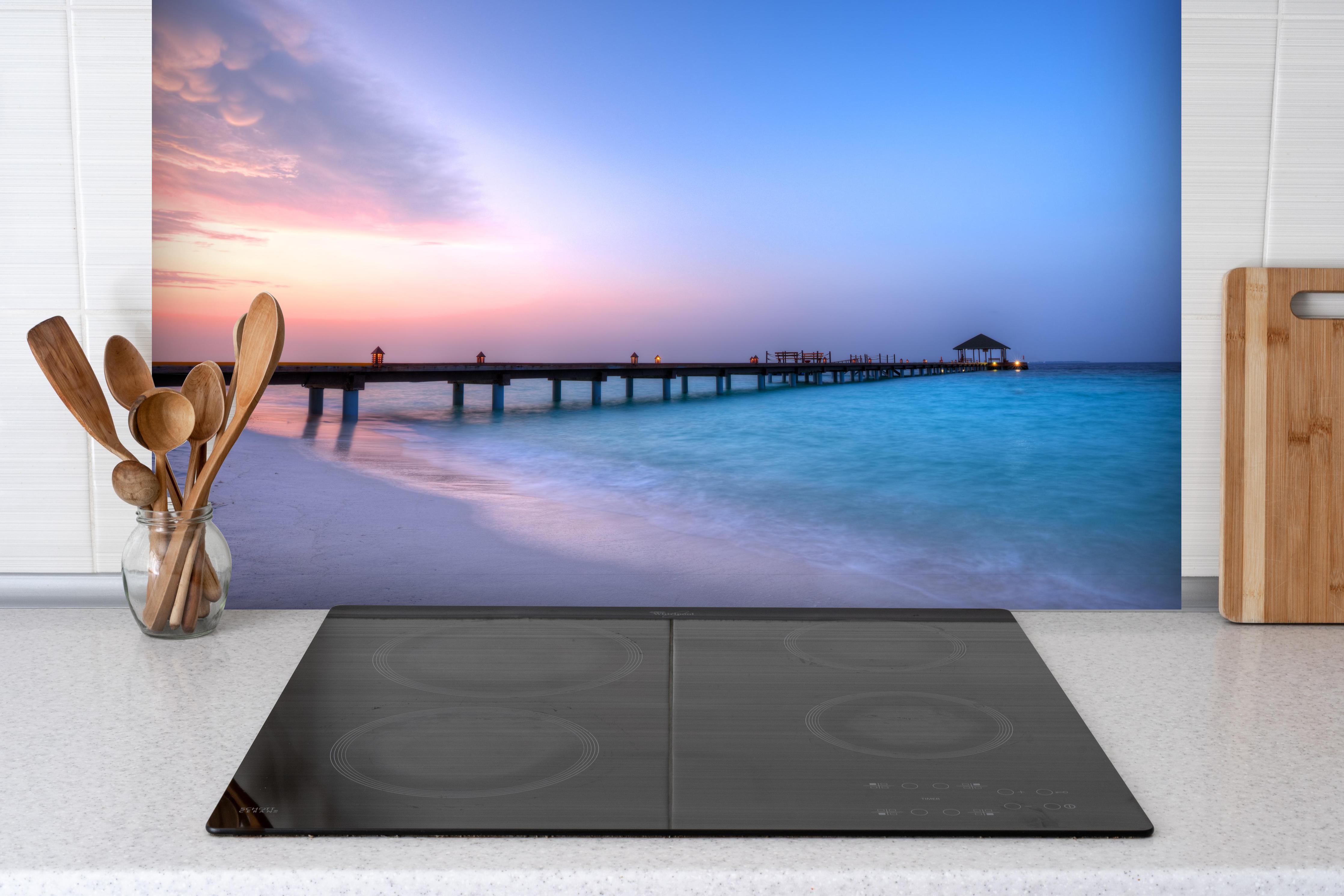 Spritzschutz - Hölzerner Steg über türkisem Meer hinter einem Cerankochfeld zwischen Holz-Kochutensilien