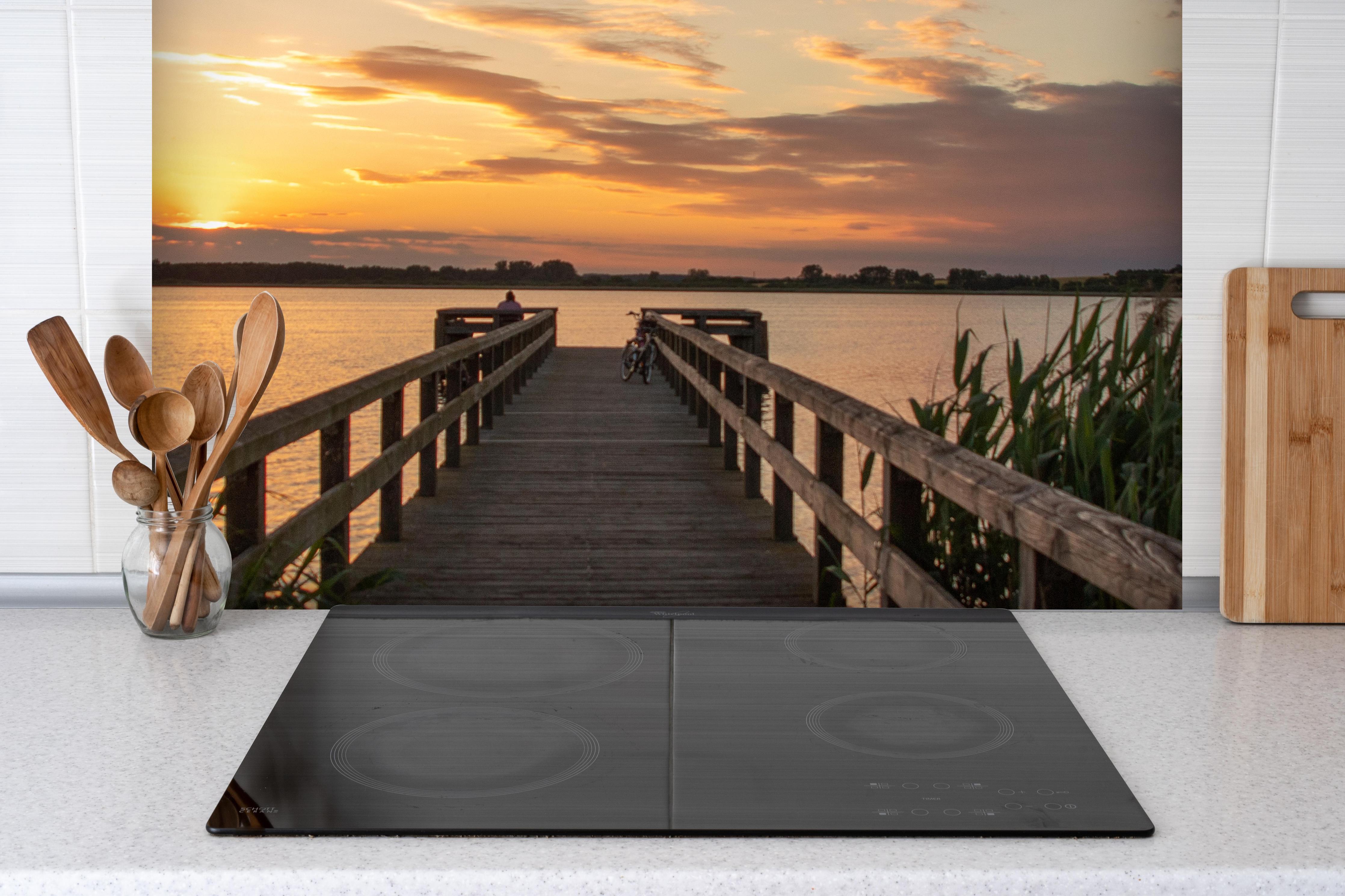 Spritzschutz - Holzsteg am Abend - Teterower See hinter einem Cerankochfeld zwischen Holz-Kochutensilien