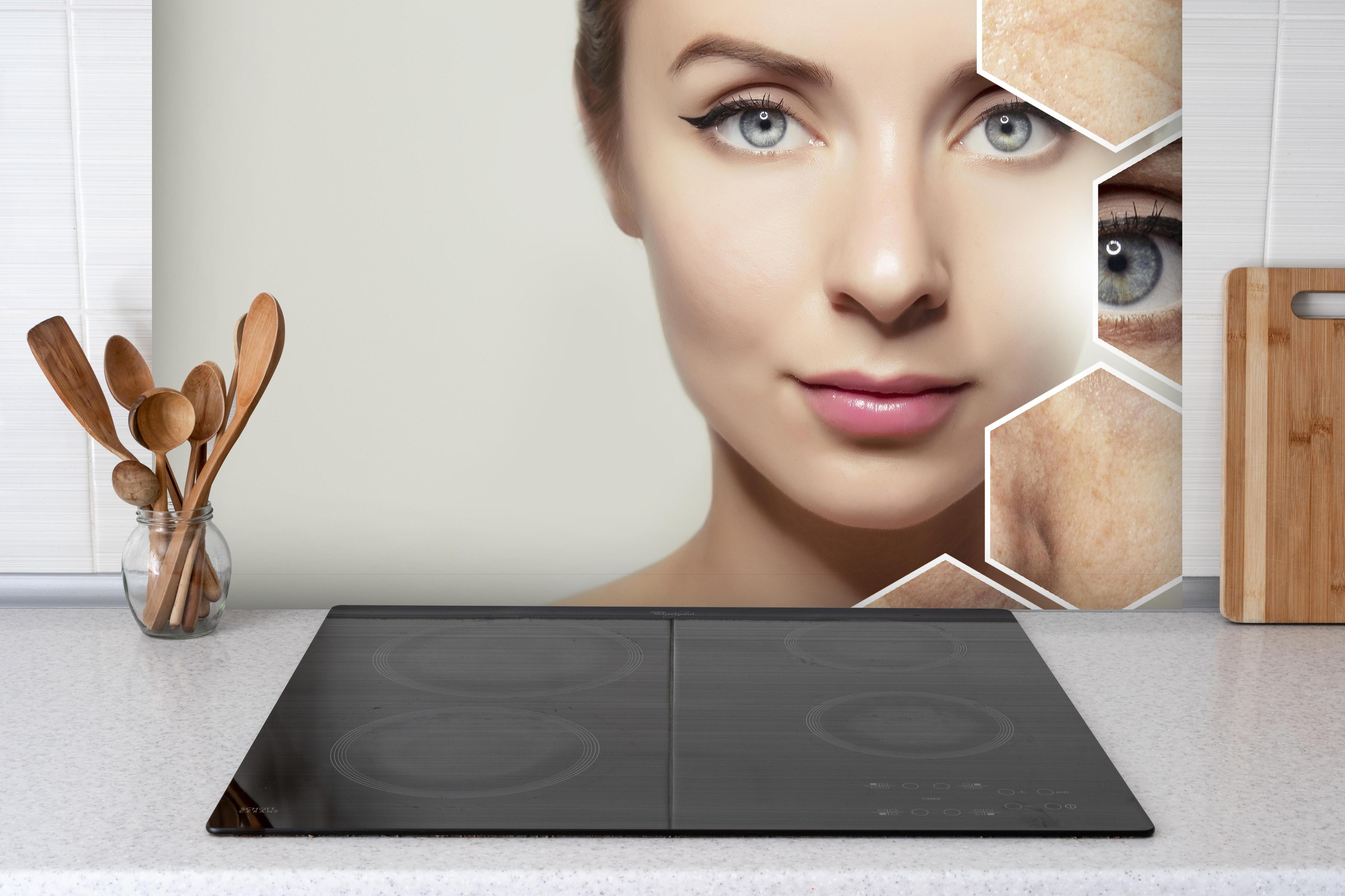 Spritzschutz - Junge Frau mit Grafikelementen alter Haut hinter einem Cerankochfeld zwischen Holz-Kochutensilien