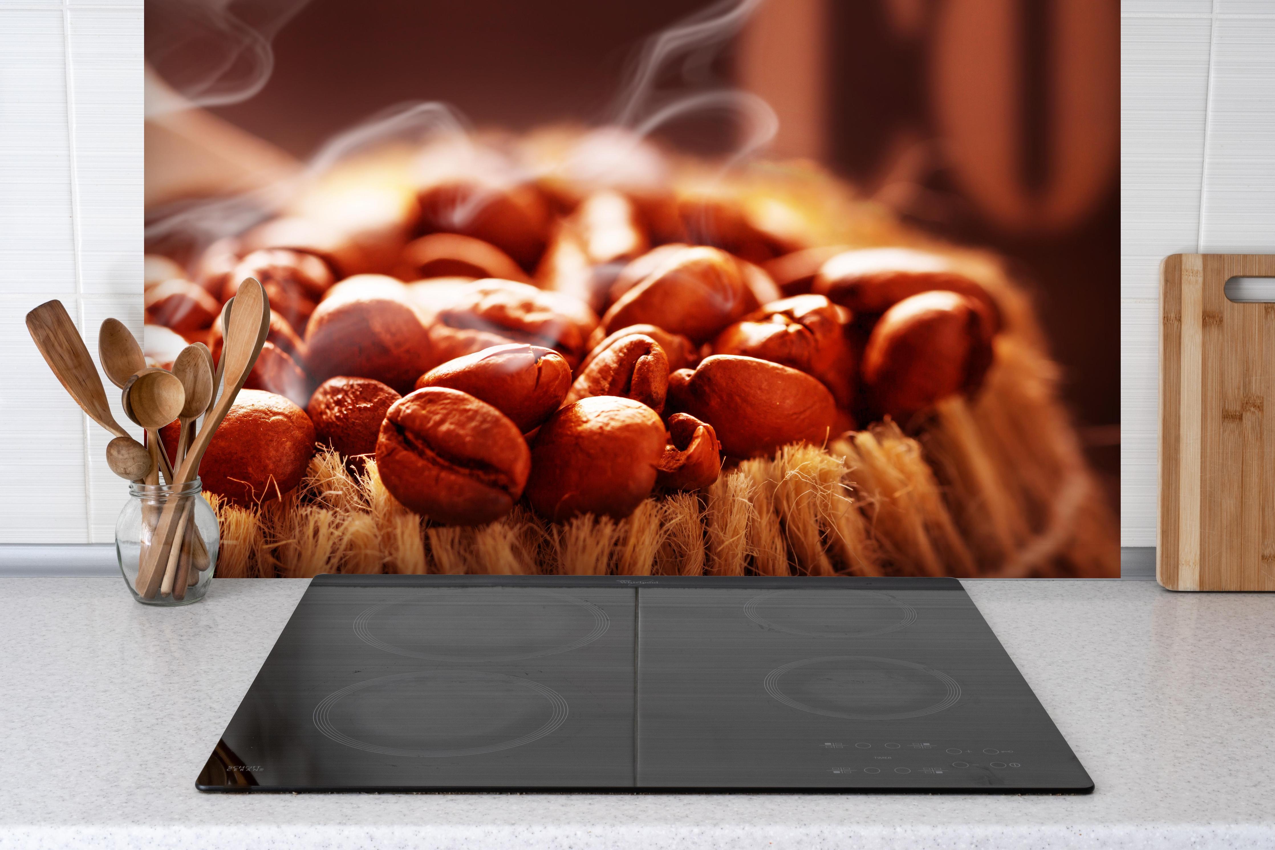 Spritzschutz - Kaffeebohnen frisch geröstet hinter einem Cerankochfeld zwischen Holz-Kochutensilien