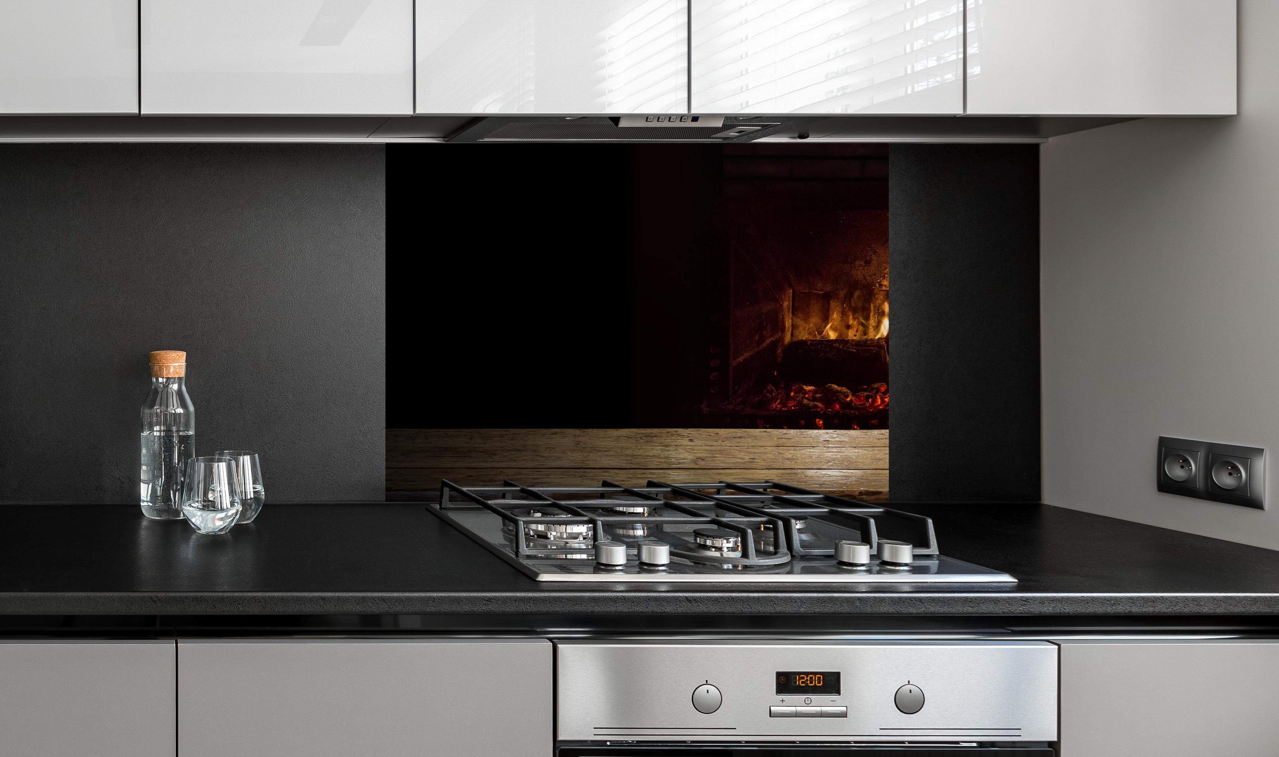 Spritzschutz - Kaminfeuer vor Holztisch an edler Anthrazit-Wand hinter silbernem Gasherd