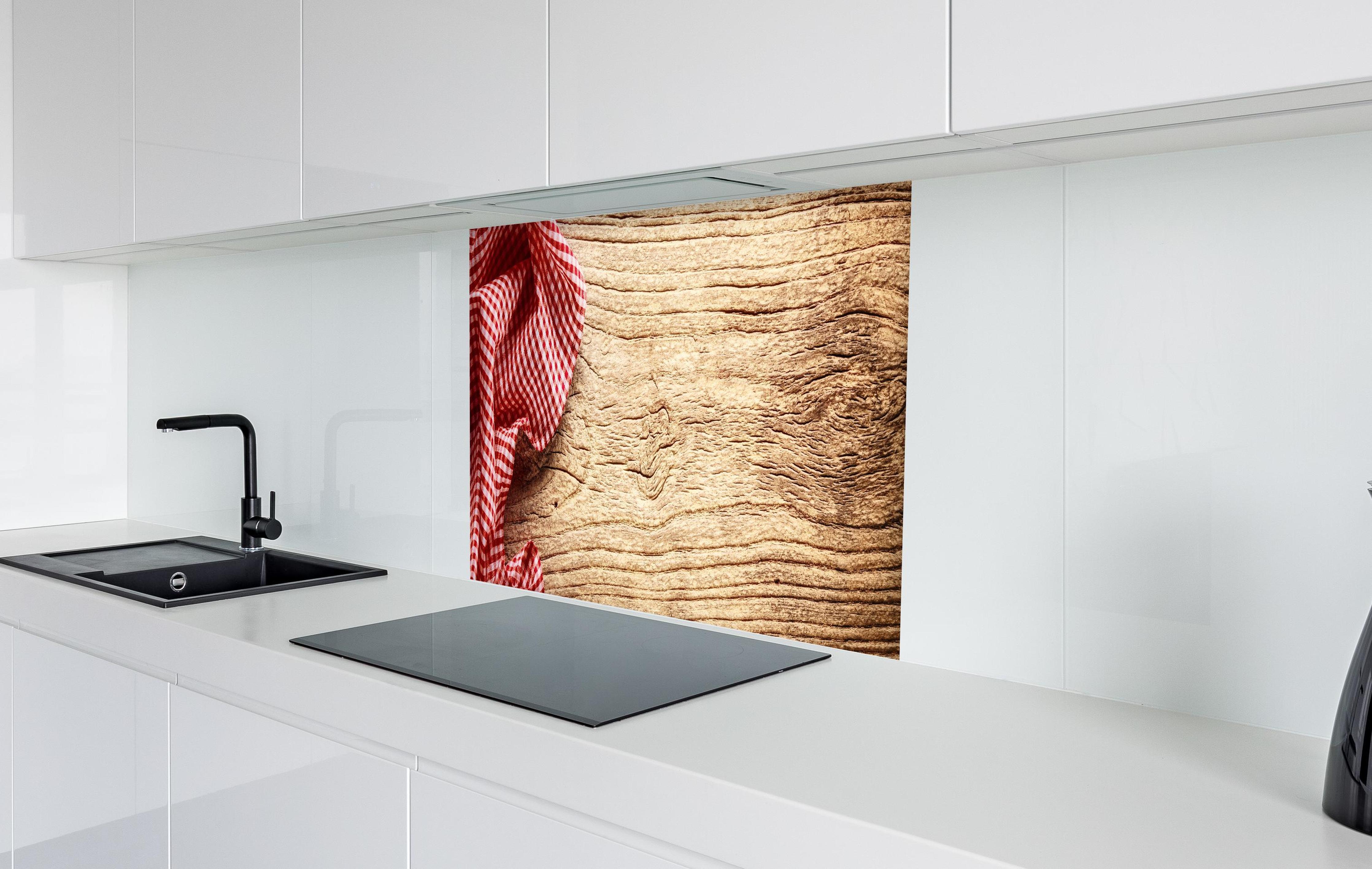 Spritzschutz - Kariertes Tischtuch auf Holztisch in weißer Hochglanz-Küche hinter einem Cerankochfeld
