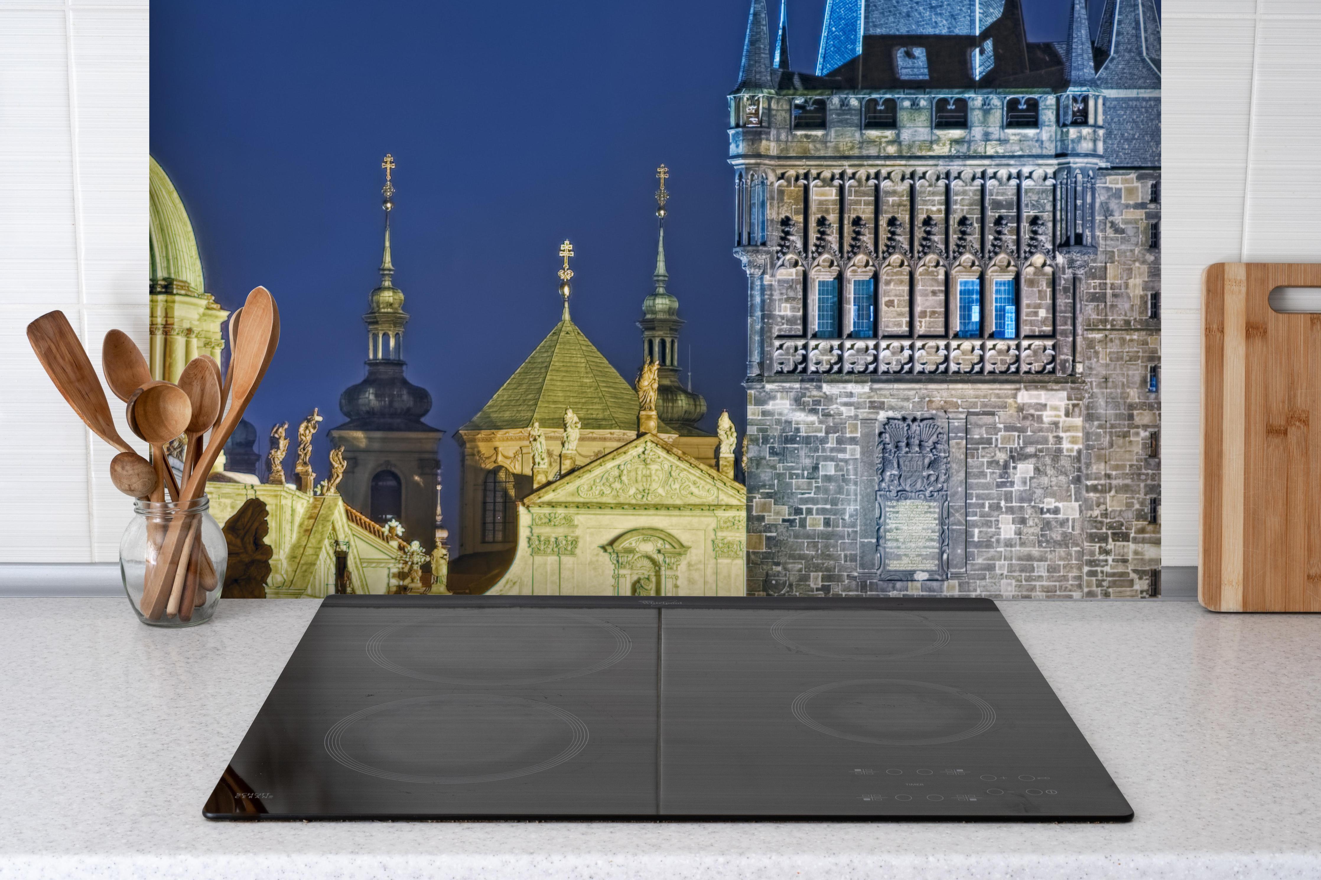 Spritzschutz - Karlsbrücke Prag beleuchtet hinter einem Cerankochfeld zwischen Holz-Kochutensilien