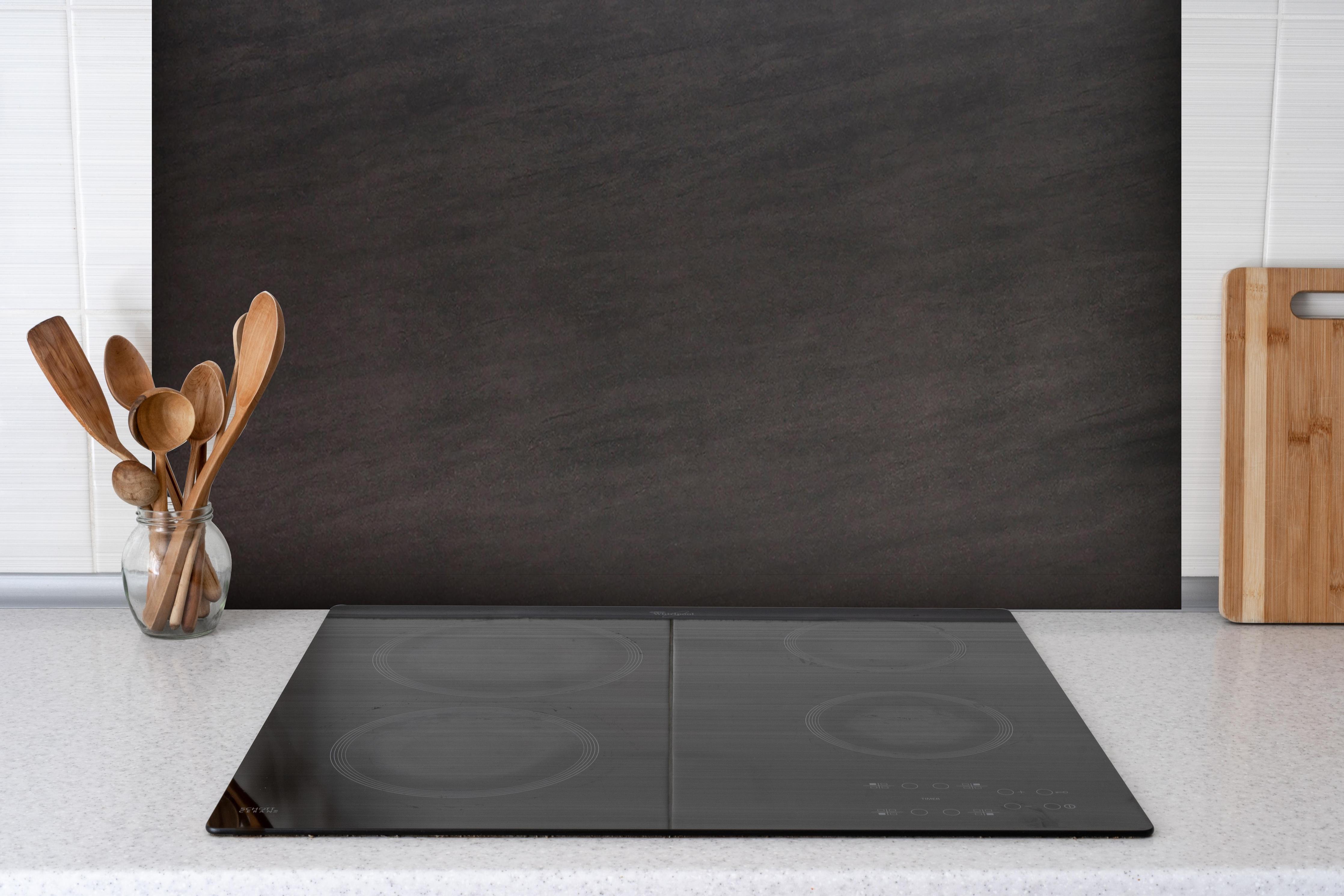 Spritzschutz - Keramik Midnight Black hinter einem Cerankochfeld zwischen Holz-Kochutensilien