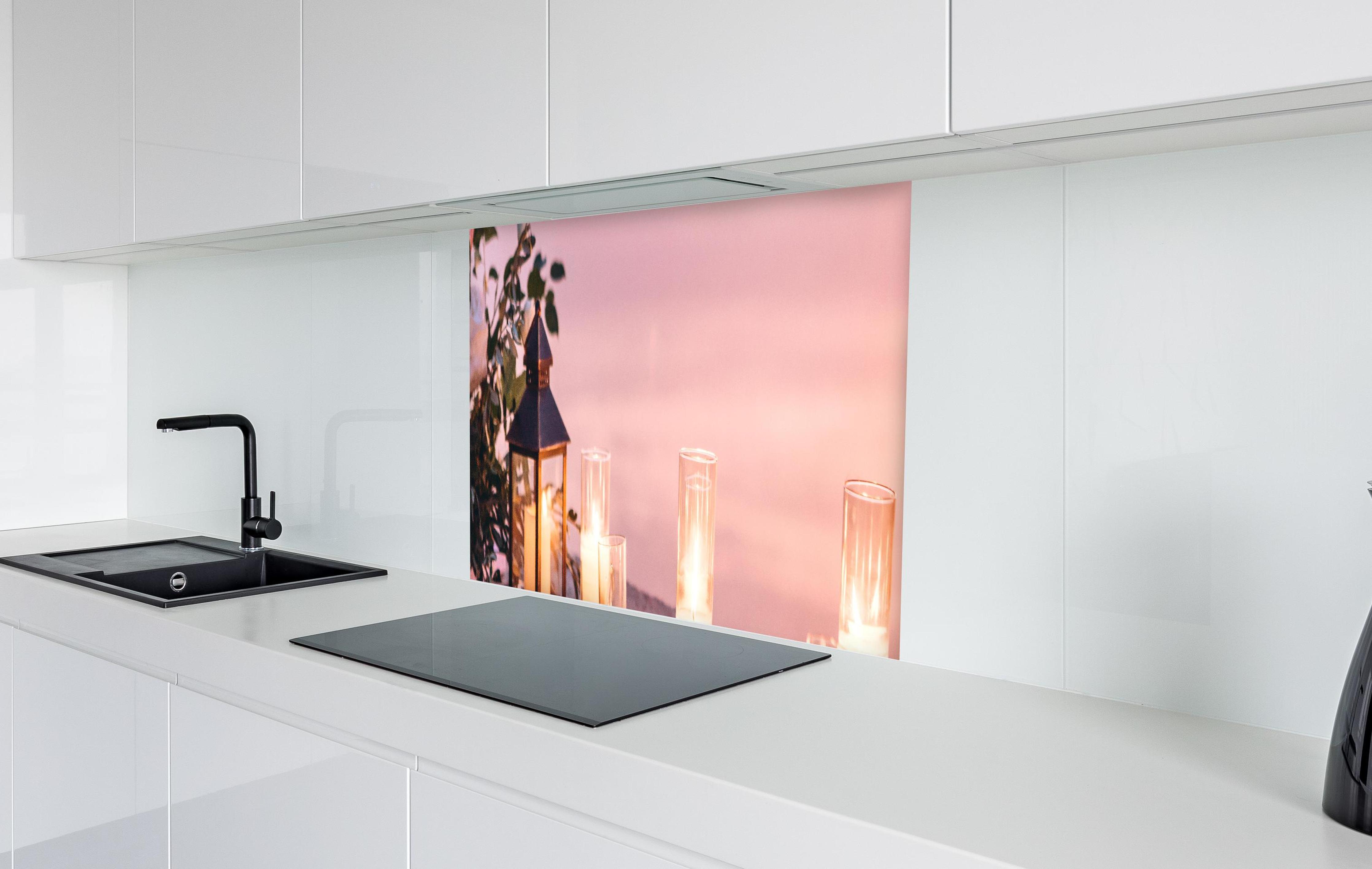 Spritzschutz - Kerzen und Blumen auf Steinmauer in weißer Hochglanz-Küche hinter einem Cerankochfeld