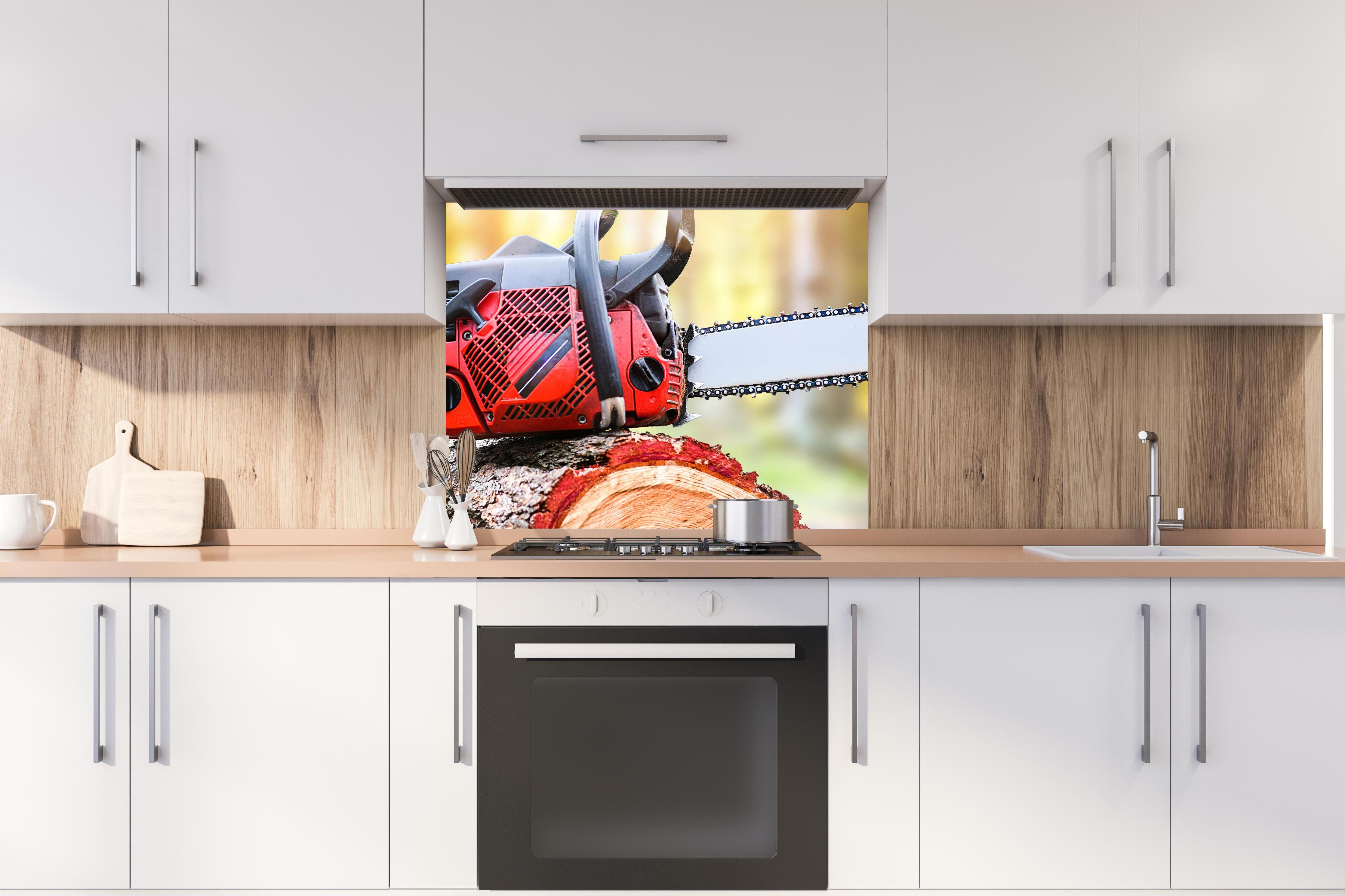 Spritzschutz - Kettensäge auf Holzstumpf hinter stilvollem Gasherd unter Dunstabzugshaube