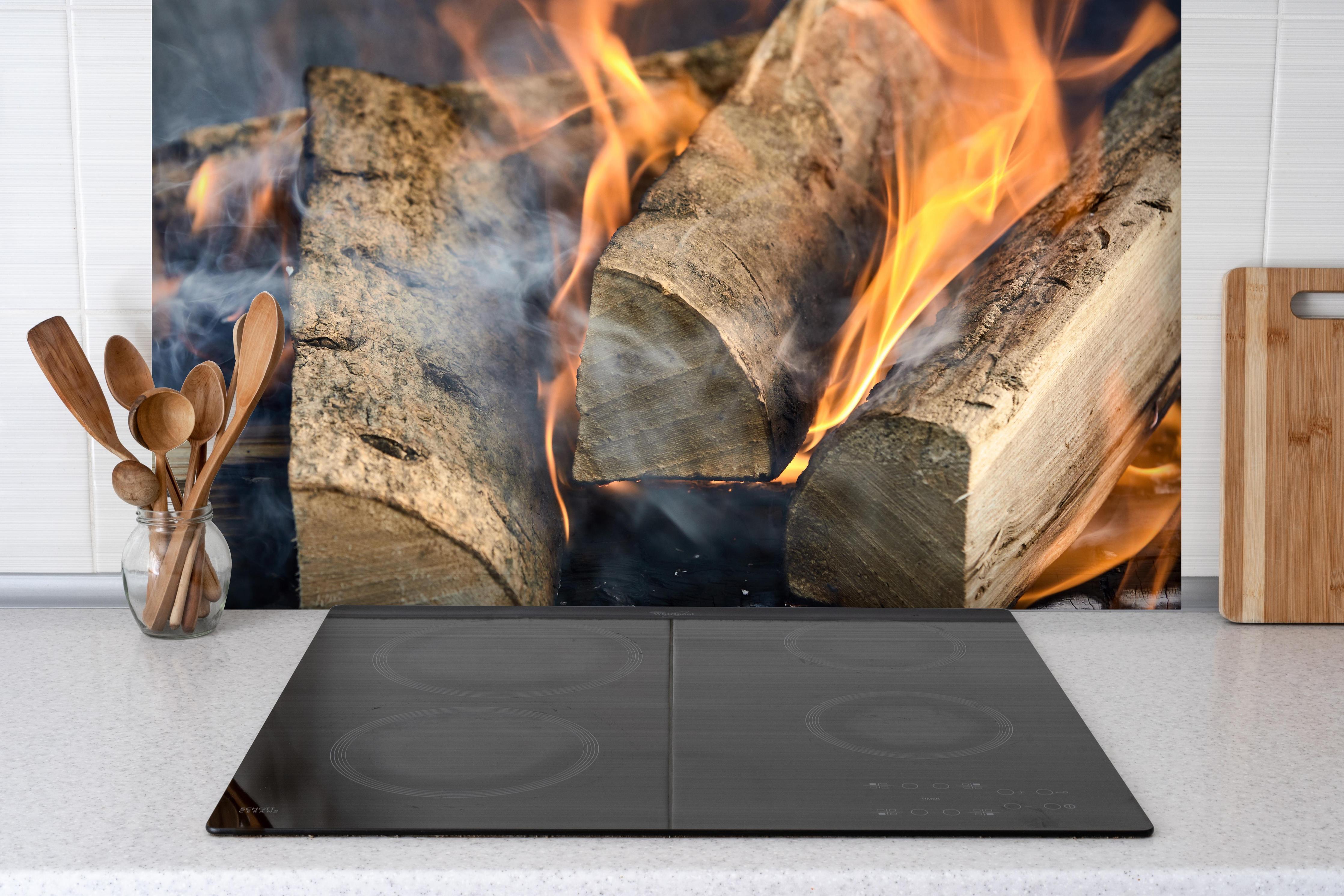 Spritzschutz - Klassisches Feuer hinter einem Cerankochfeld zwischen Holz-Kochutensilien