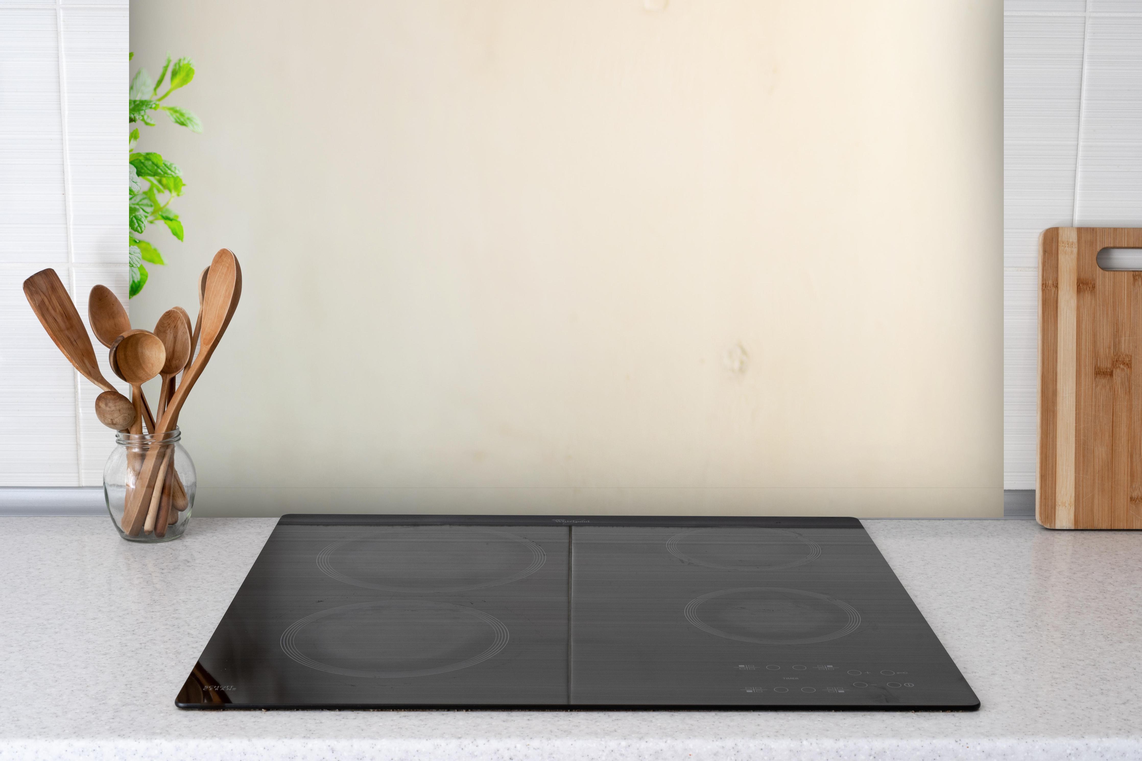 Spritzschutz - Kleiner feiner Blumentopf hinter einem Cerankochfeld zwischen Holz-Kochutensilien