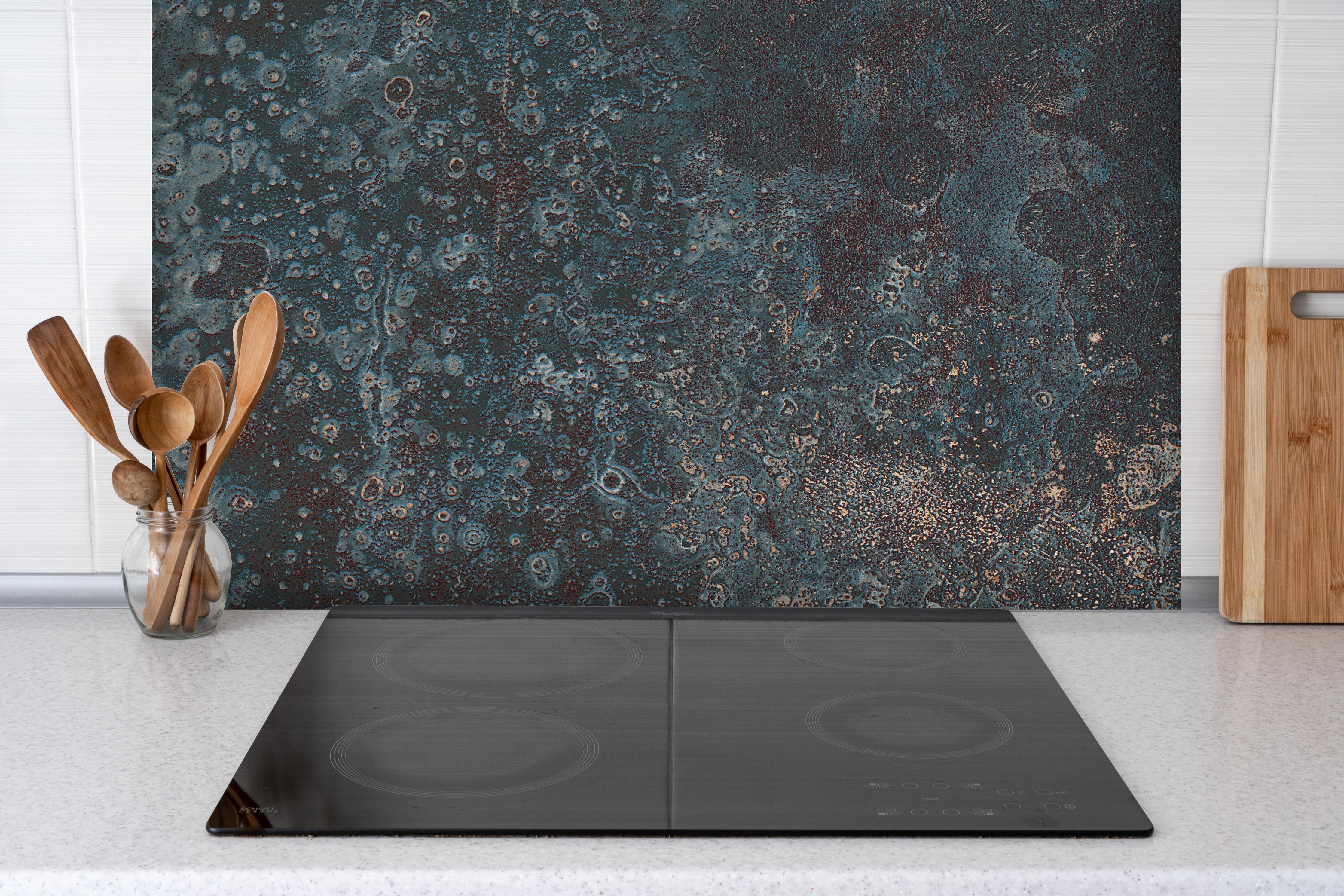 Spritzschutz - Korrodiertes Eisen Muster hinter einem Cerankochfeld zwischen Holz-Kochutensilien