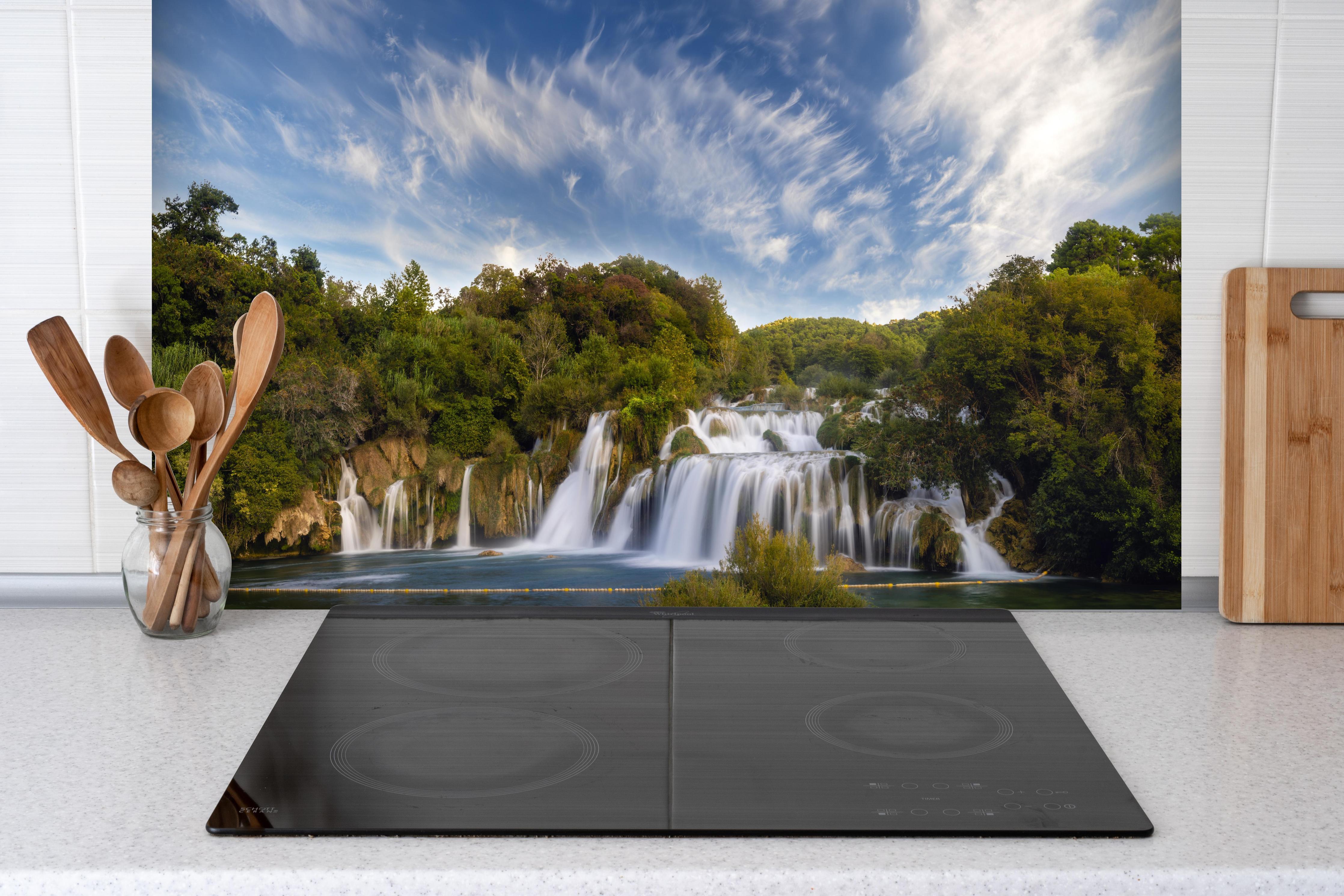 Spritzschutz - Krka-Nationalpark-Panorama hinter einem Cerankochfeld zwischen Holz-Kochutensilien