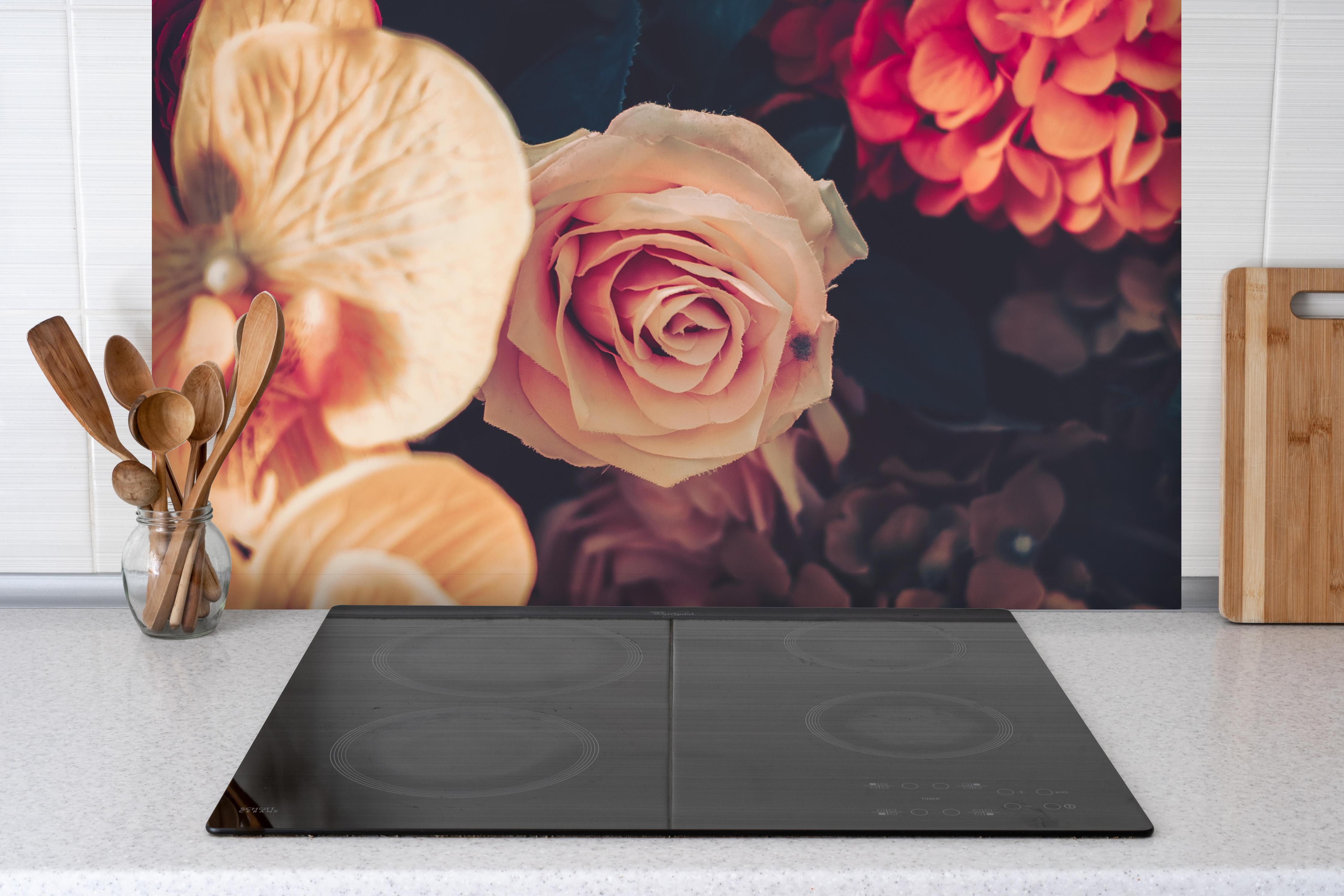 Spritzschutz - Künstliche Sommerblumen im Vintage-Stil hinter einem Cerankochfeld zwischen Holz-Kochutensilien