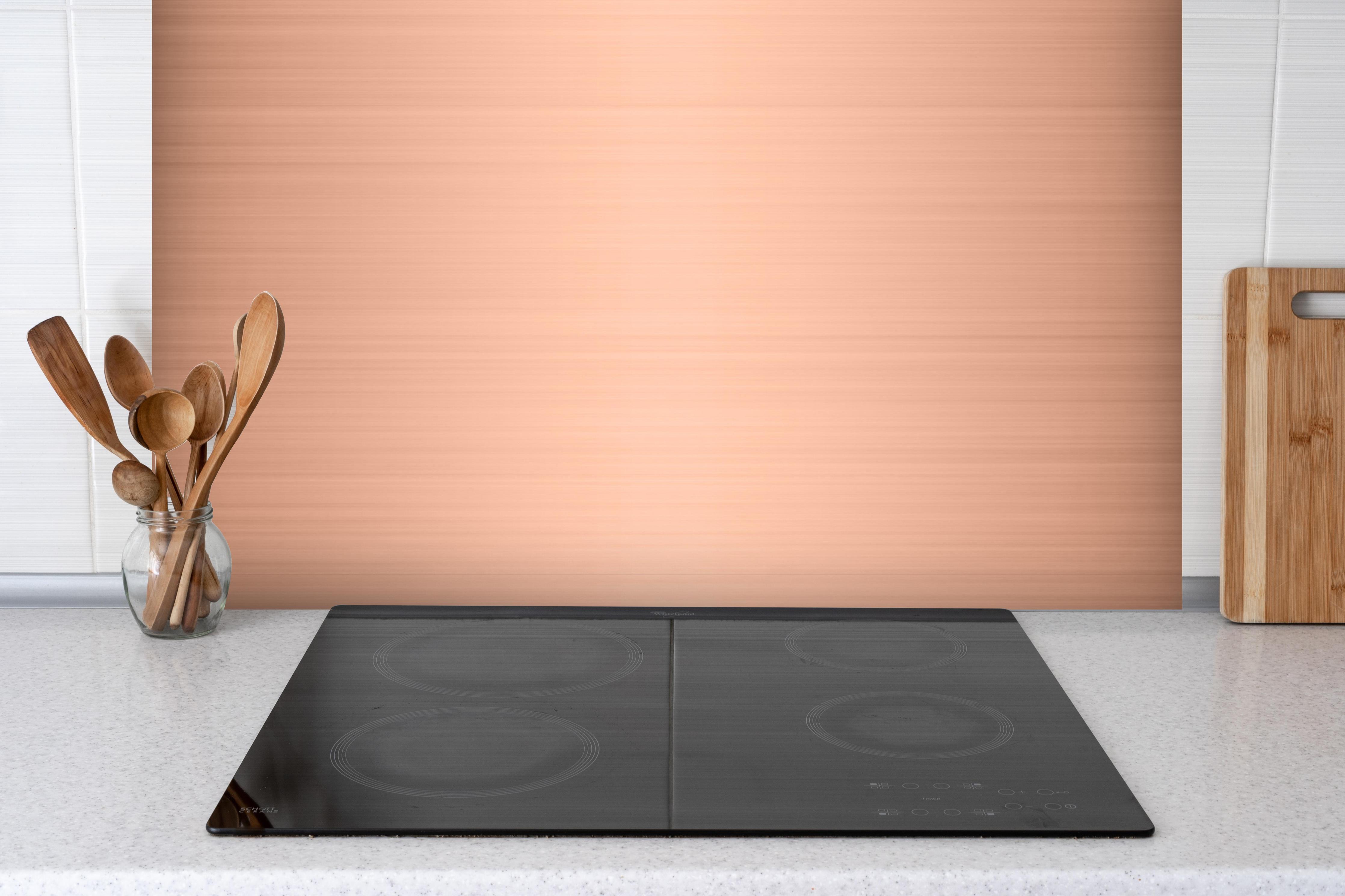 Spritzschutz - Kupfer belichtet hinter einem Cerankochfeld zwischen Holz-Kochutensilien