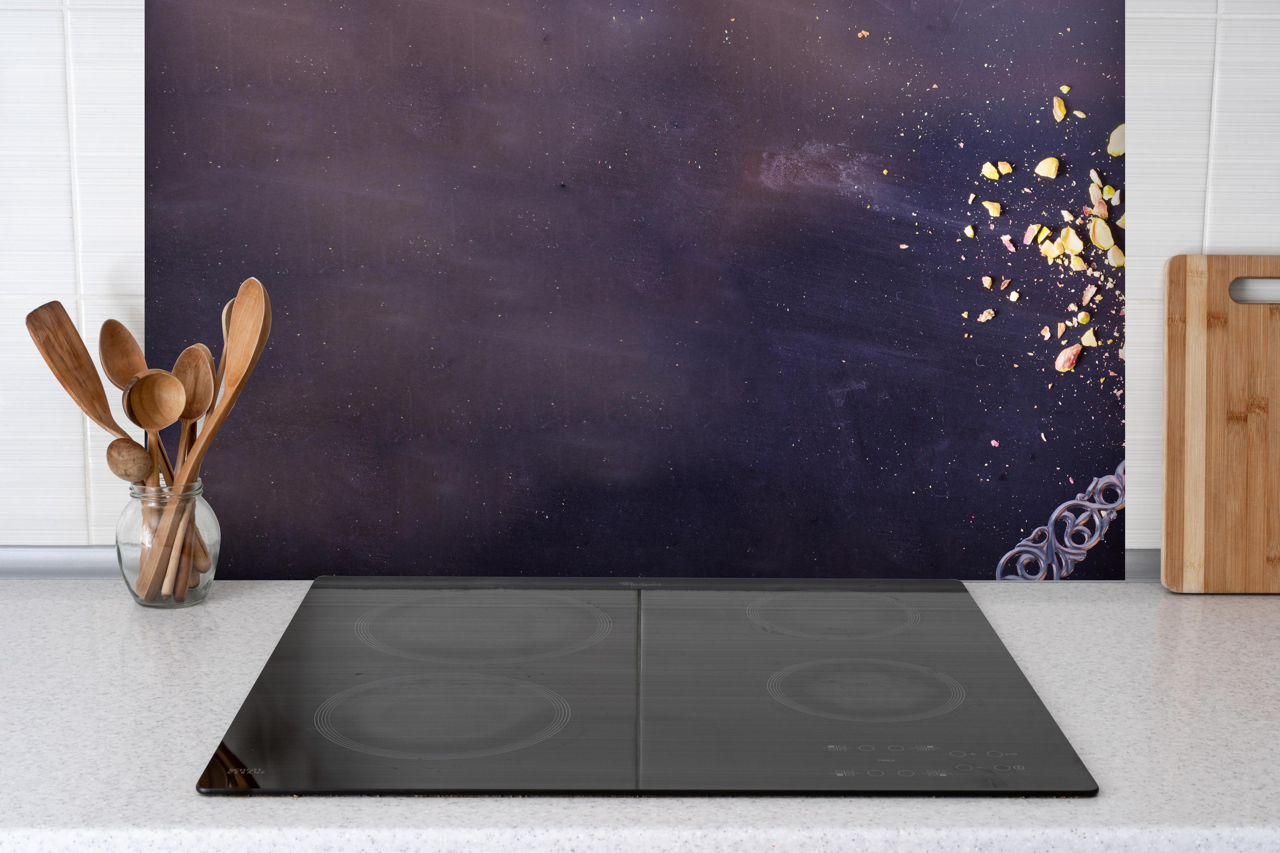 Spritzschutz - Leckerer Himbeerkuchen hinter einem Cerankochfeld zwischen Holz-Kochutensilien