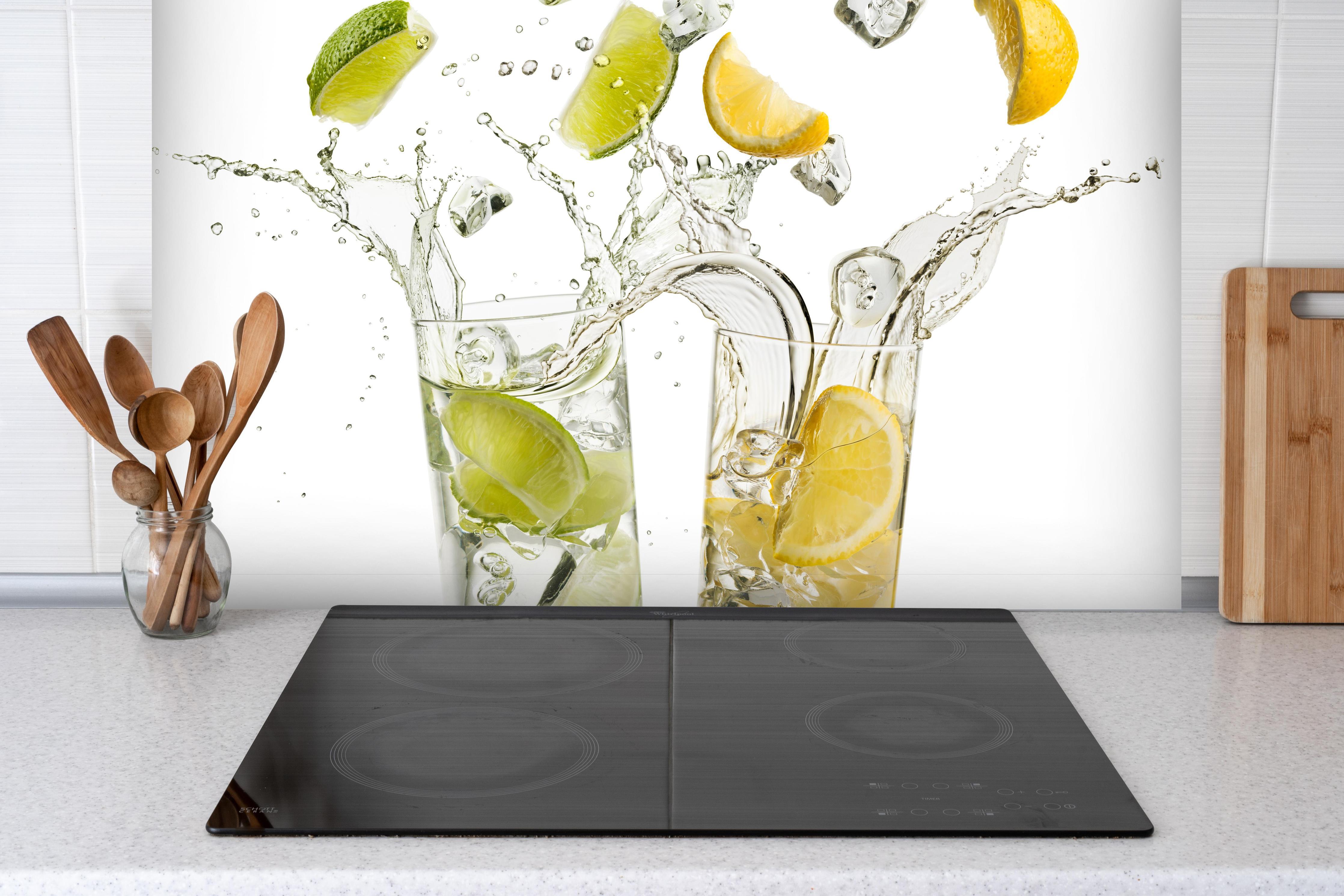 Spritzschutz - Limetten-Zitronen Getränk hinter einem Cerankochfeld zwischen Holz-Kochutensilien