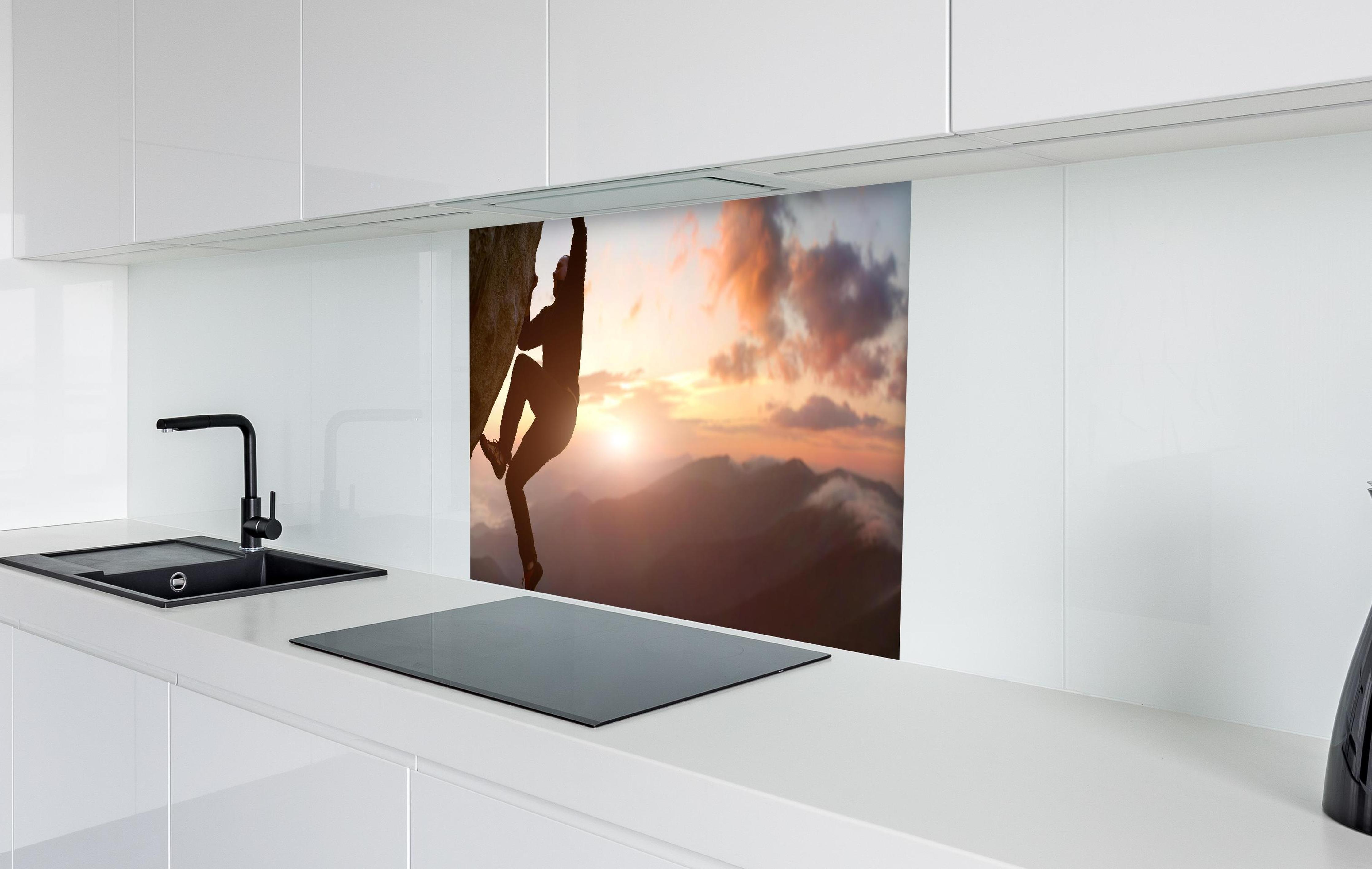 Spritzschutz - Männlicher Kletterer bei Sonnenuntergang in weißer Hochglanz-Küche hinter einem Cerankochfeld