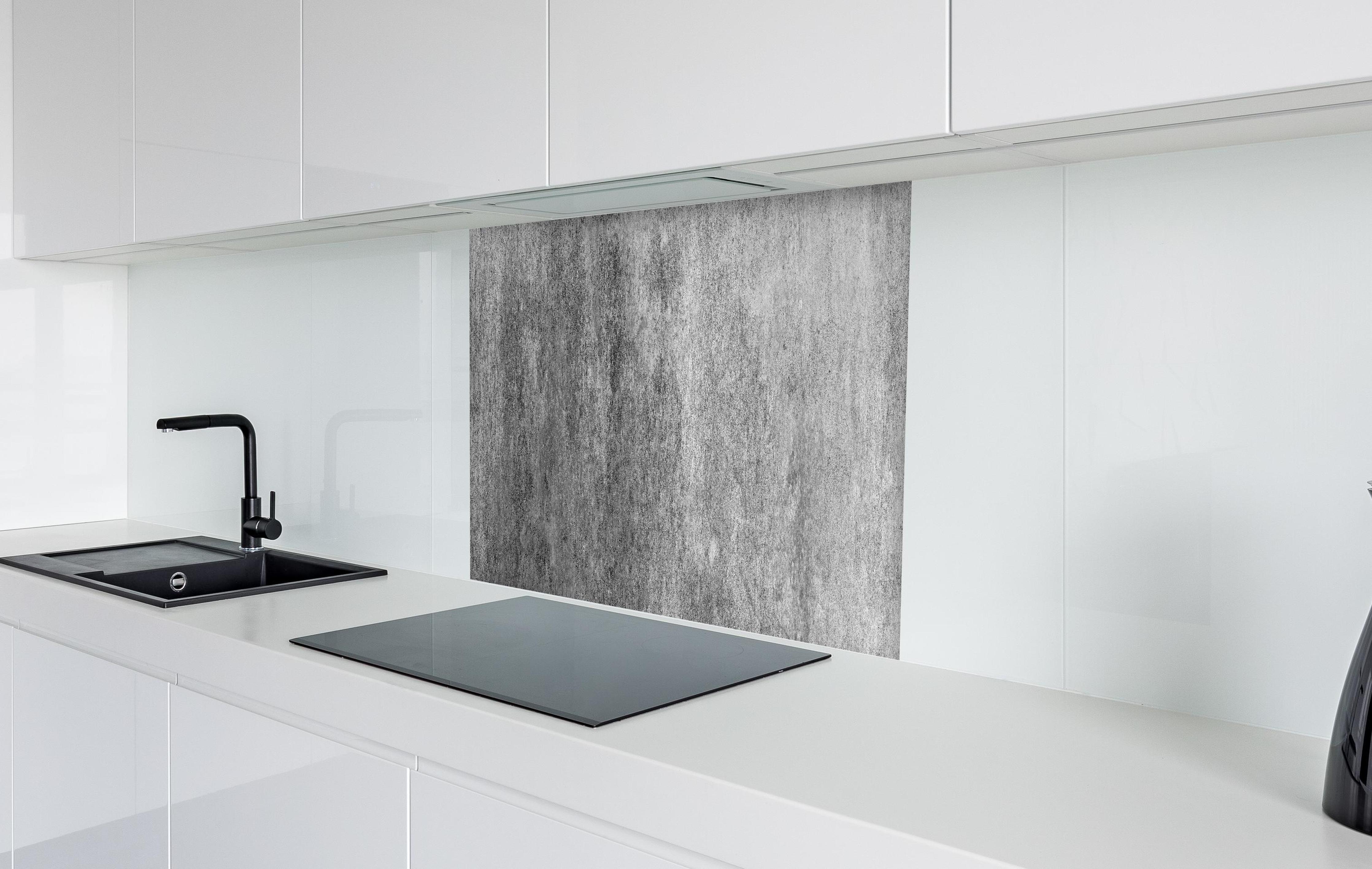 Spritzschutz - Massiver dunkelgrauer Beton in weißer Hochglanz-Küche hinter einem Cerankochfeld