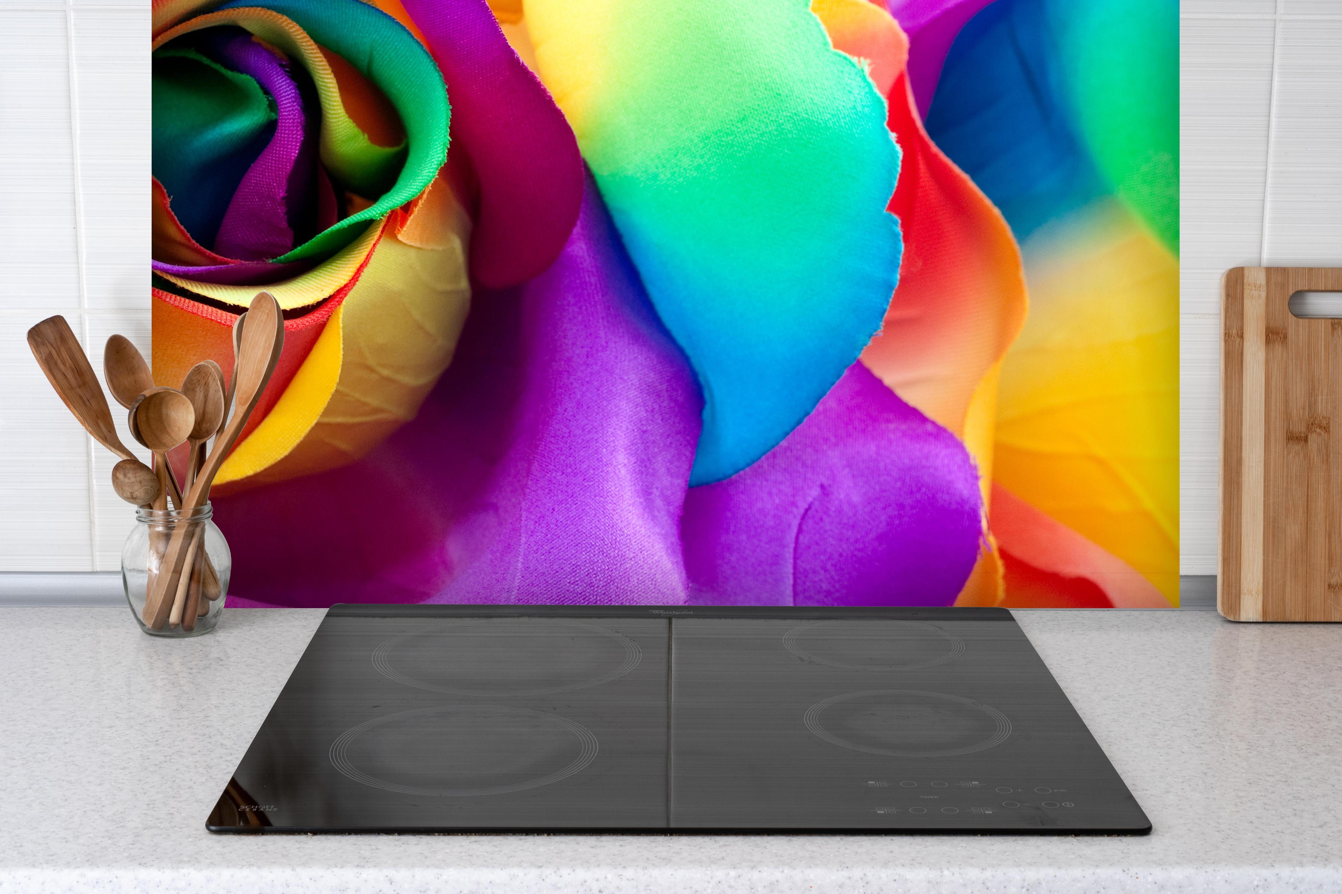 Spritzschutz - Mehrfarbige synthetische Rose hinter einem Cerankochfeld zwischen Holz-Kochutensilien