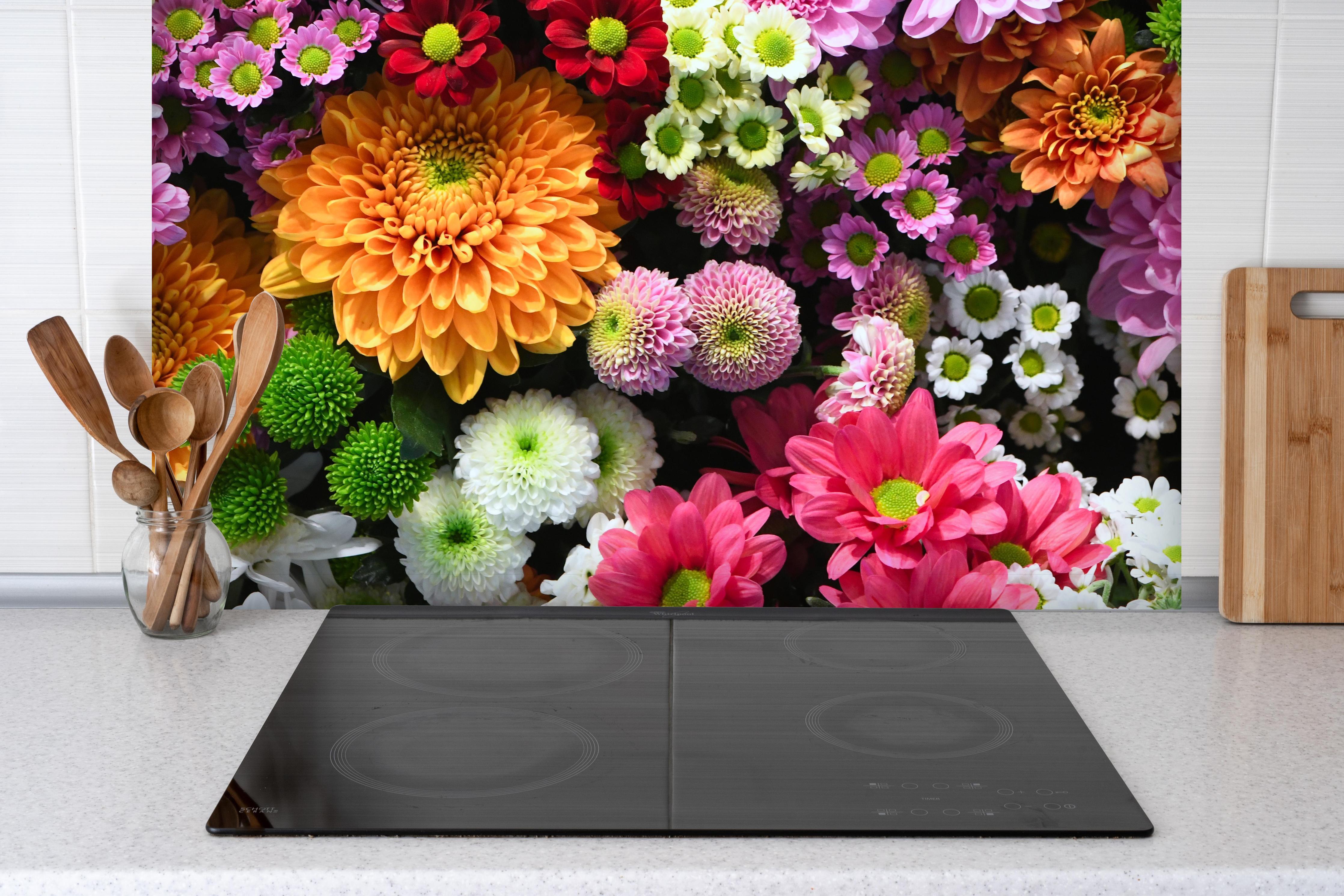Spritzschutz - Mix aus bunten Frühlingsblumen hinter einem Cerankochfeld zwischen Holz-Kochutensilien
