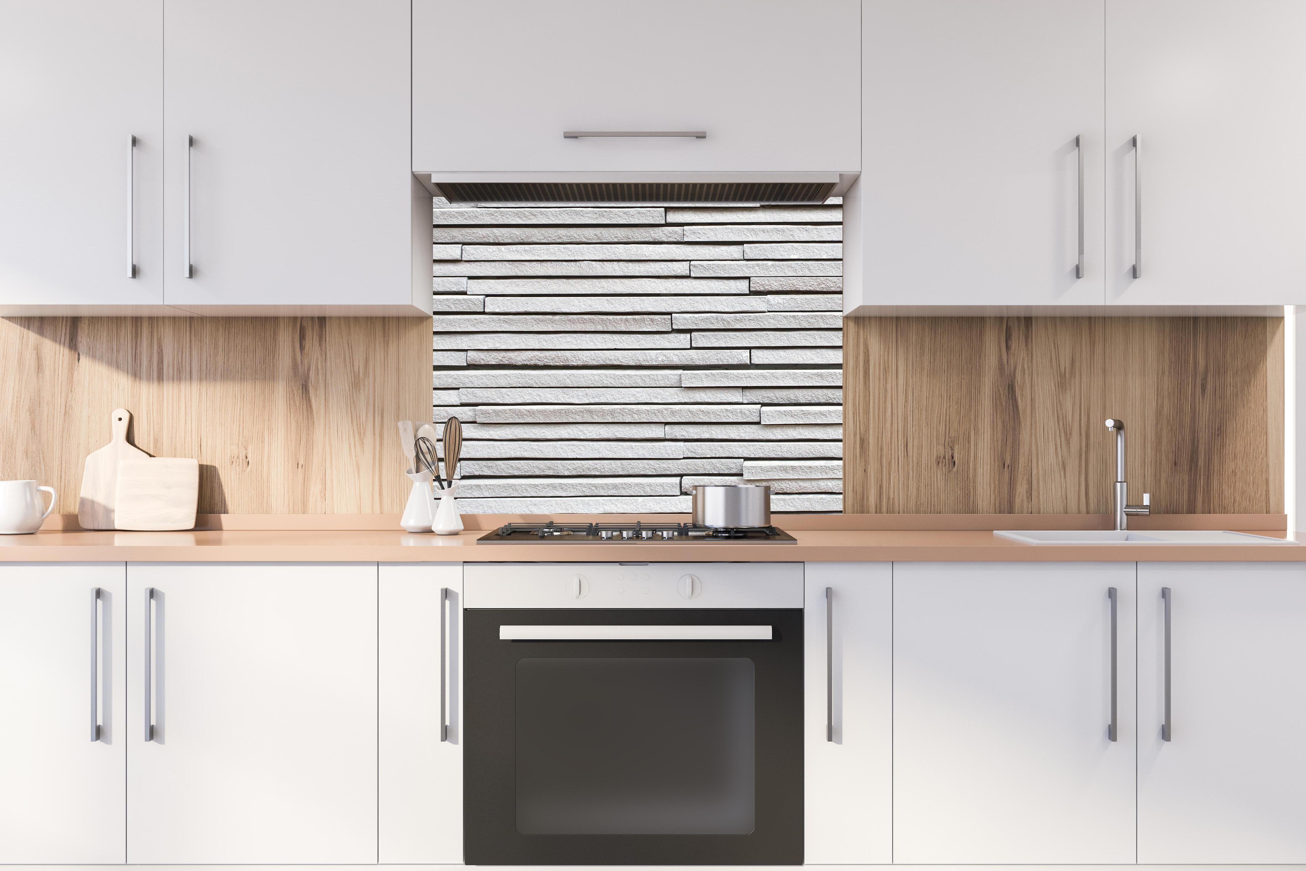 Spritzschutz - Moderne helle Steinwand hinter stilvollem Gasherd unter Dunstabzugshaube