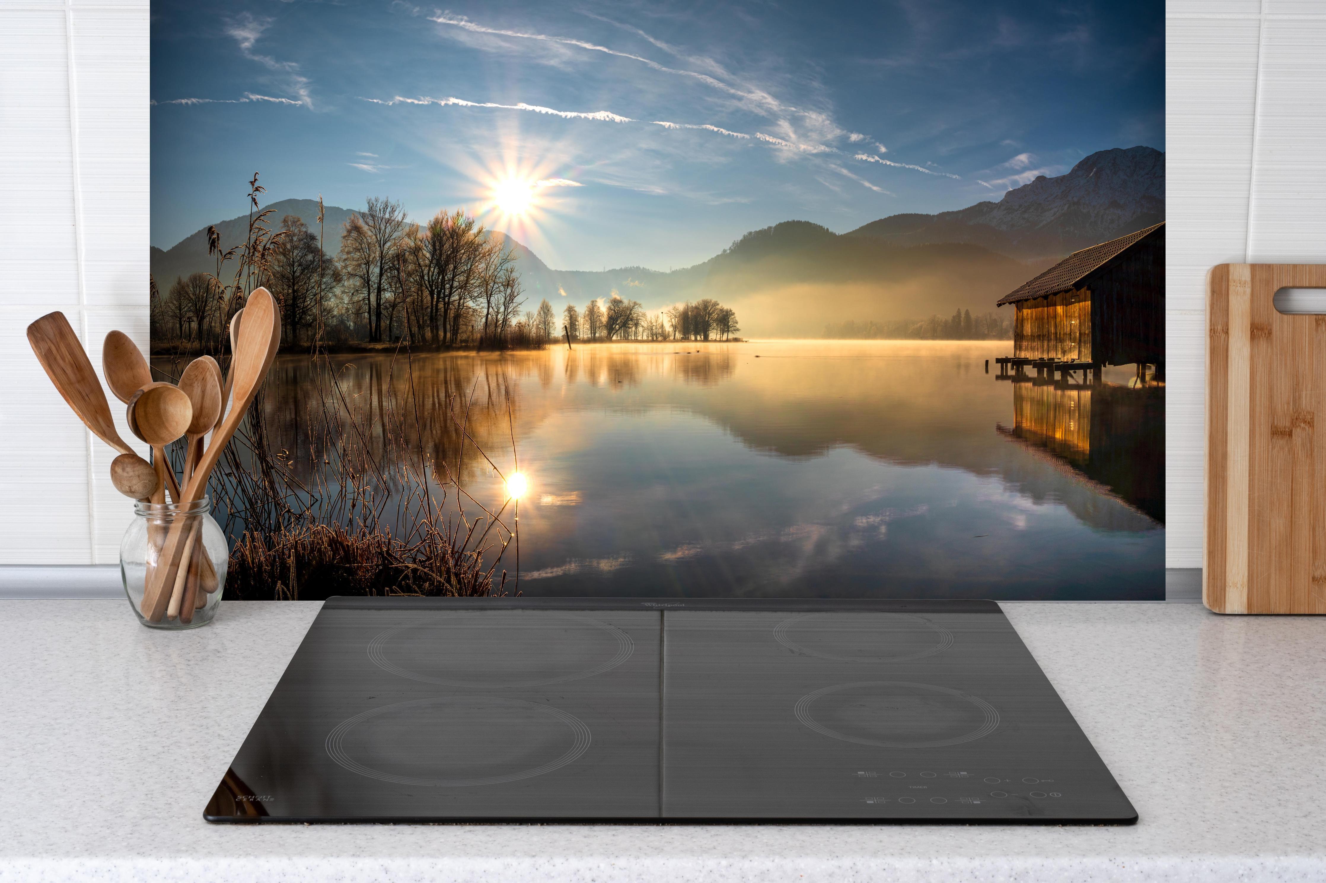 Spritzschutz - Morgensonnenblick auf den Bayerischen Kochelsee hinter einem Cerankochfeld zwischen Holz-Kochutensilien
