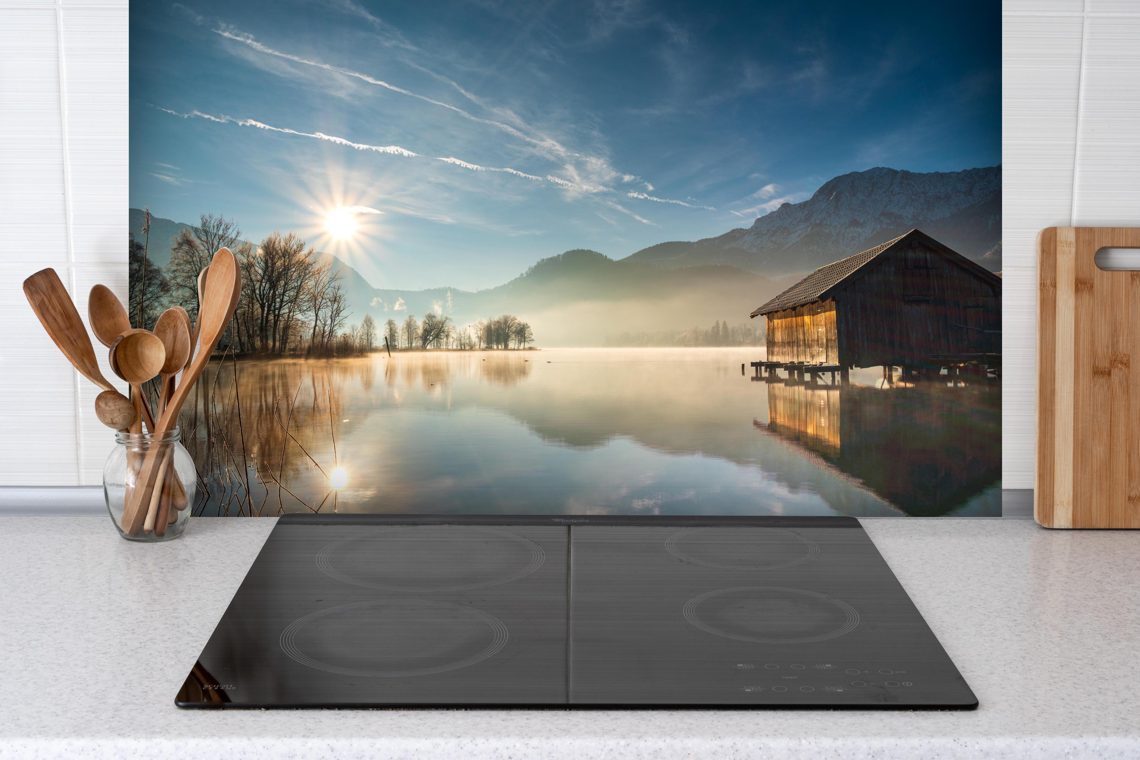 Spritzschutz - Morgensonnenblick über Bayerischen Kochelsee hinter einem Cerankochfeld zwischen Holz-Kochutensilien