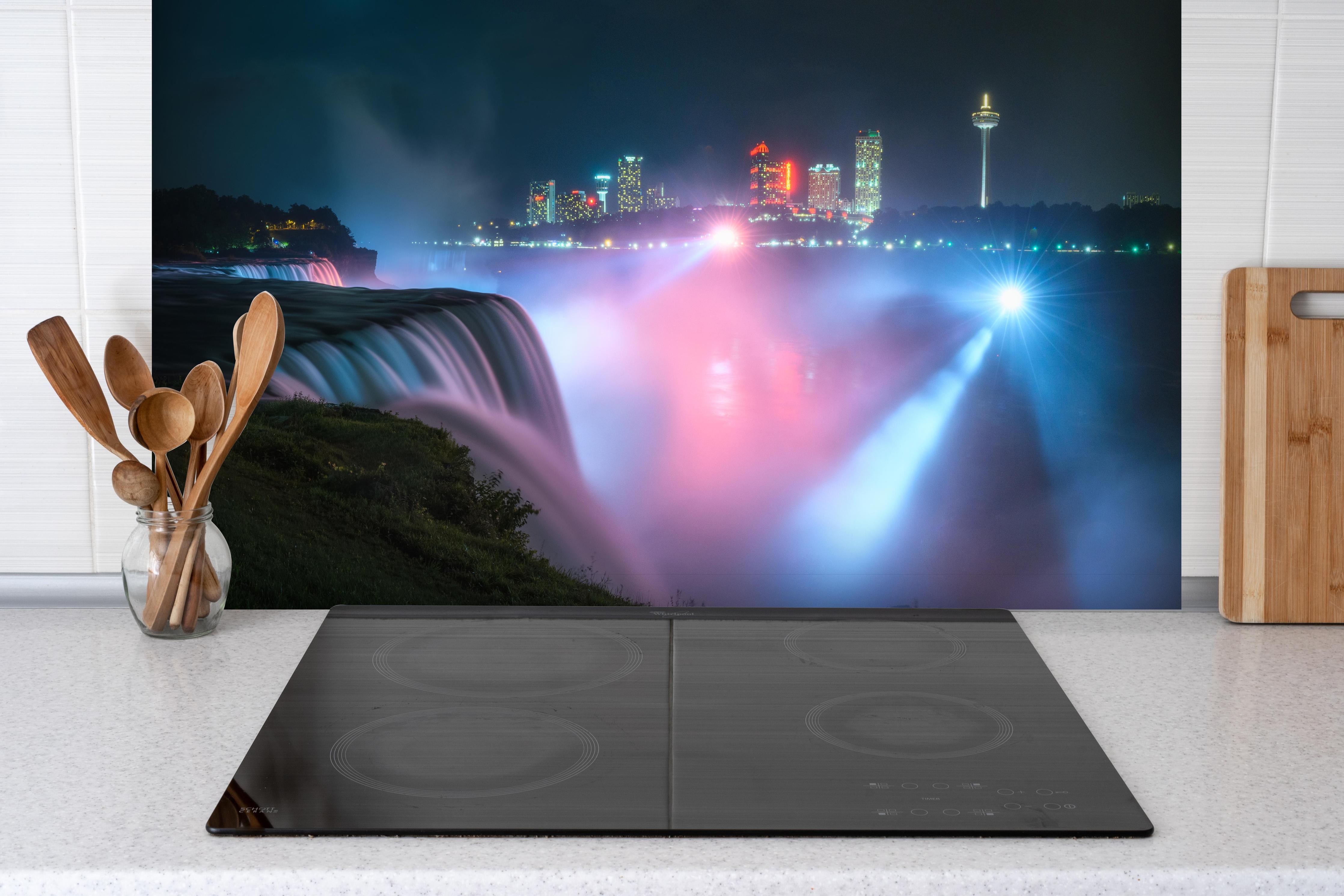 Spritzschutz - Niagarafälle bei Nacht hinter einem Cerankochfeld zwischen Holz-Kochutensilien
