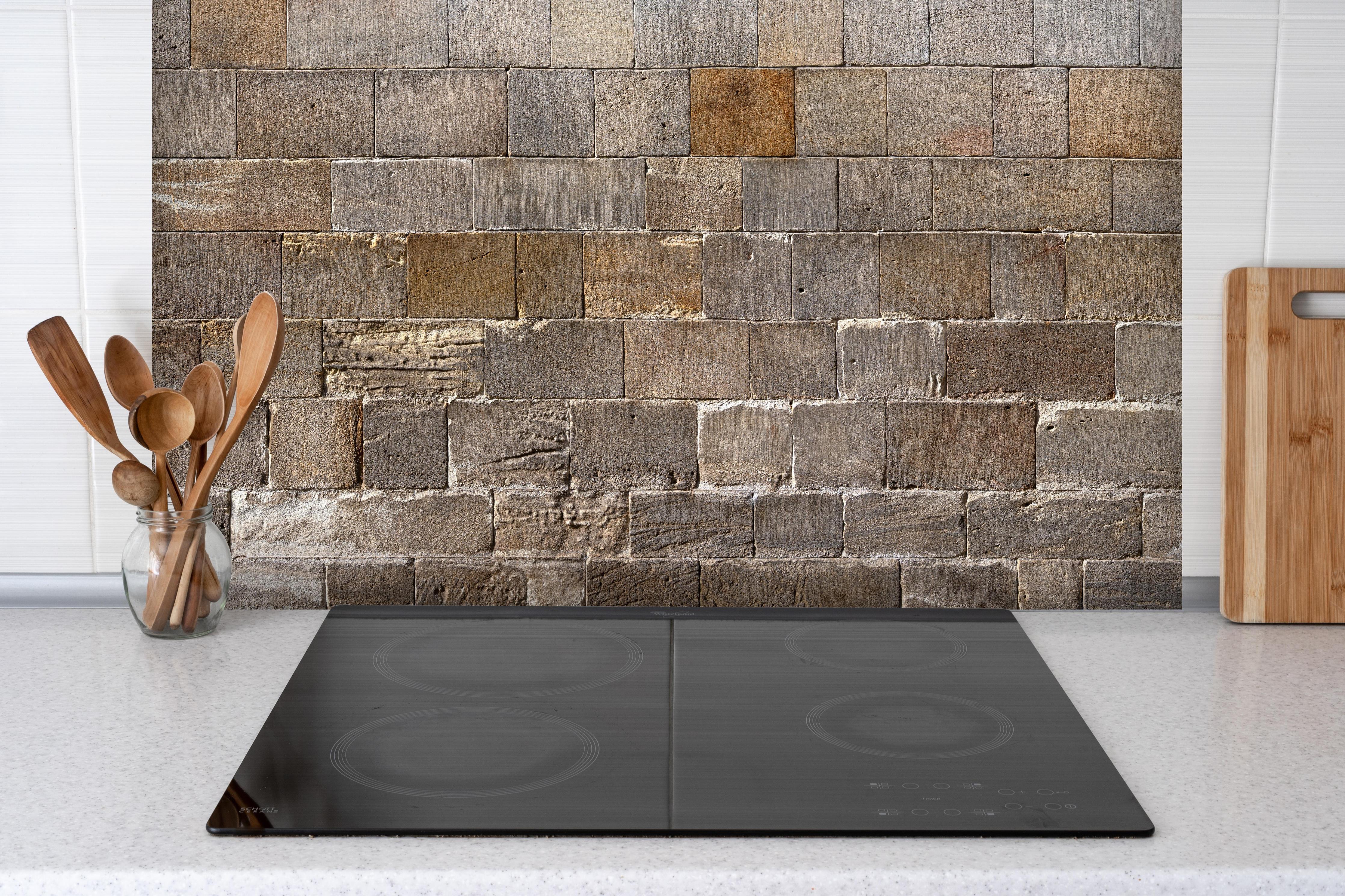 Spritzschutz - Panorama Kirchenmauer hinter einem Cerankochfeld zwischen Holz-Kochutensilien