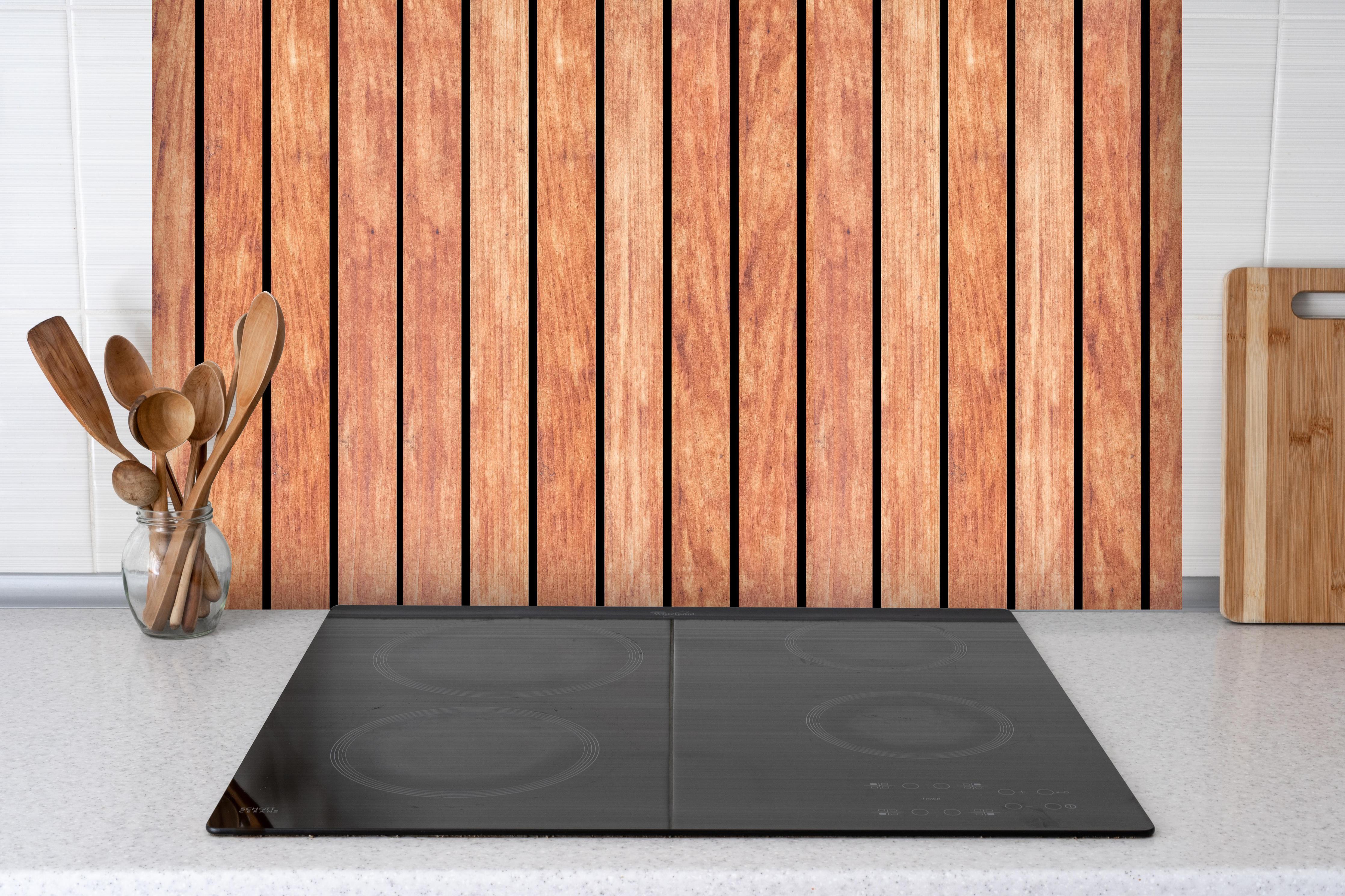 Spritzschutz - Panorama von hellen Holzplanken hinter einem Cerankochfeld zwischen Holz-Kochutensilien