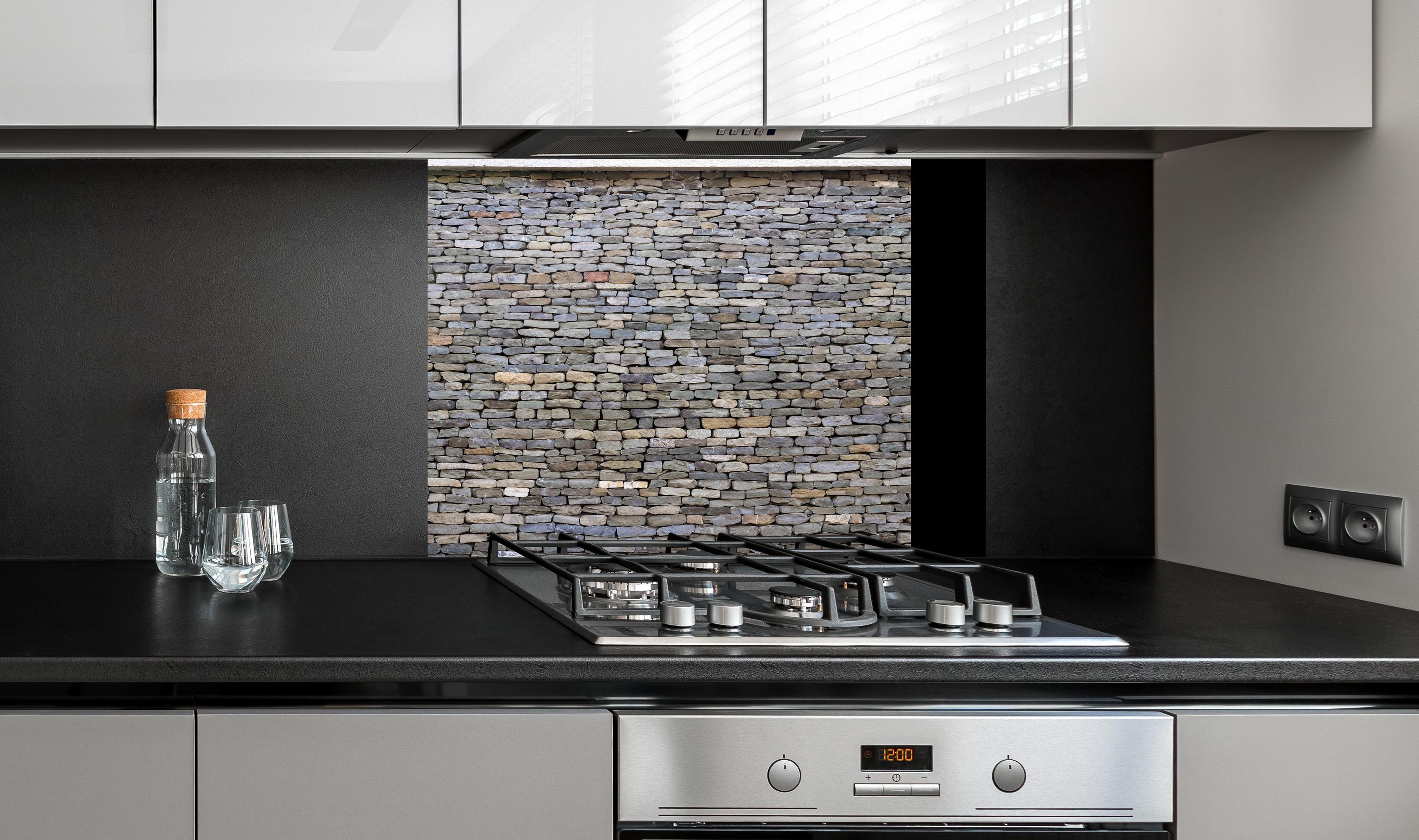 Spritzschutz - Pastellfarbene Steinmauer an edler Anthrazit-Wand hinter silbernem Gasherd